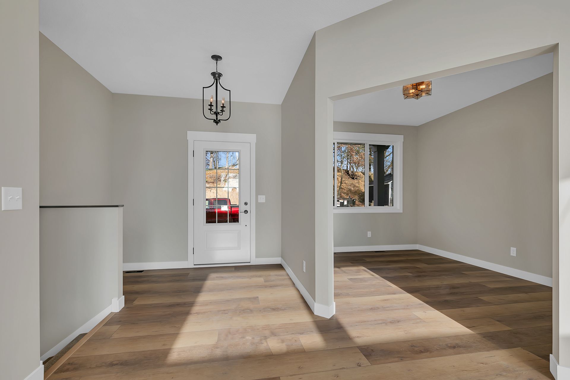 An empty living room with hardwood floors and a white door.