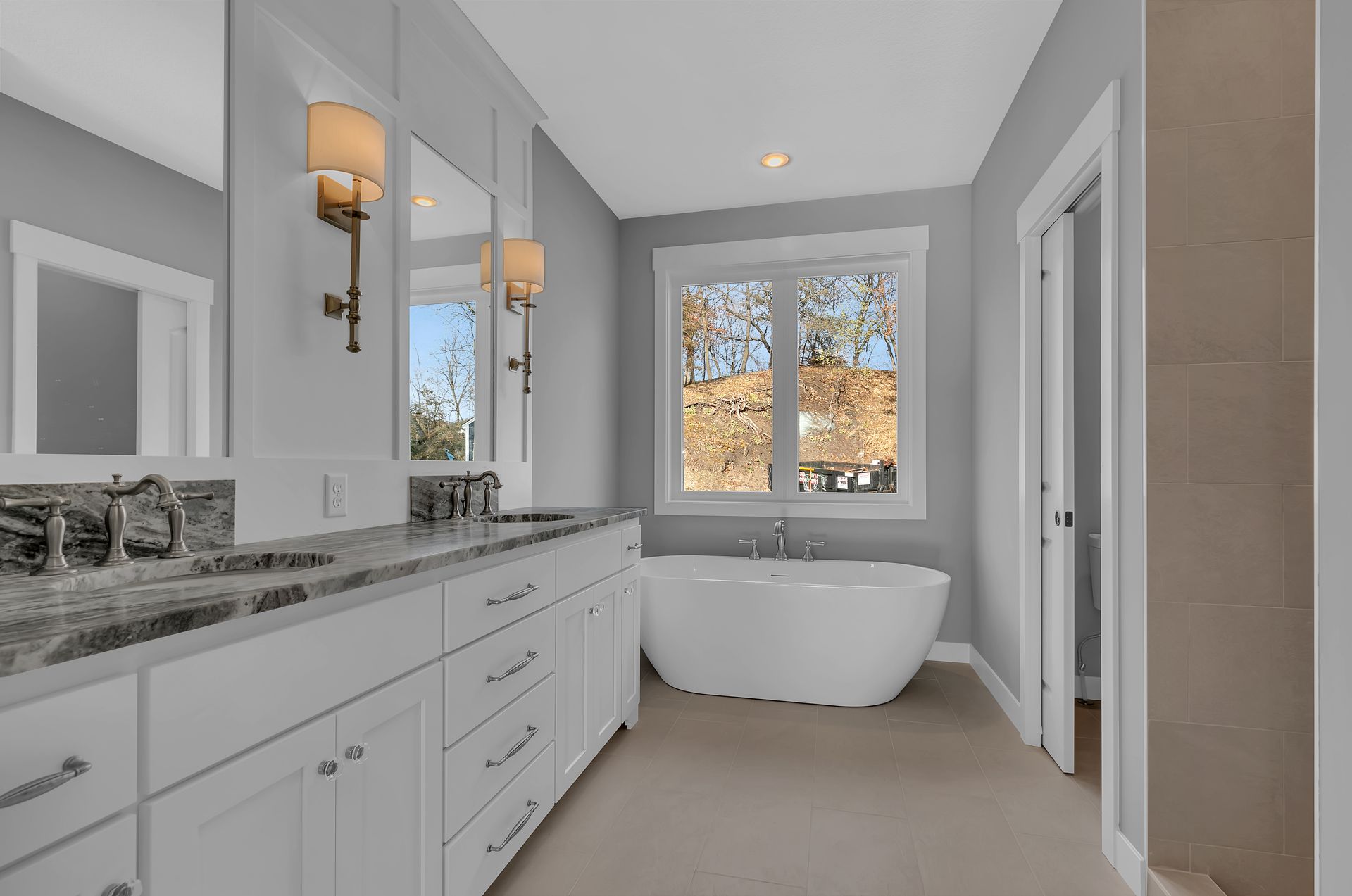 A bathroom with a tub , sinks , mirrors and a window.