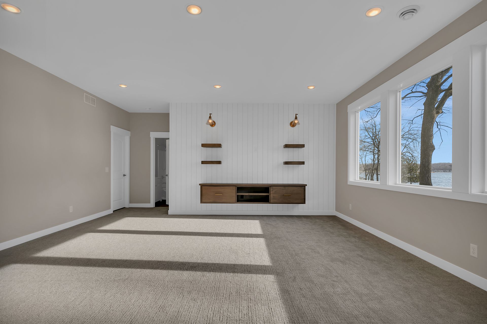 A large empty room with a lot of windows and a carpeted floor.