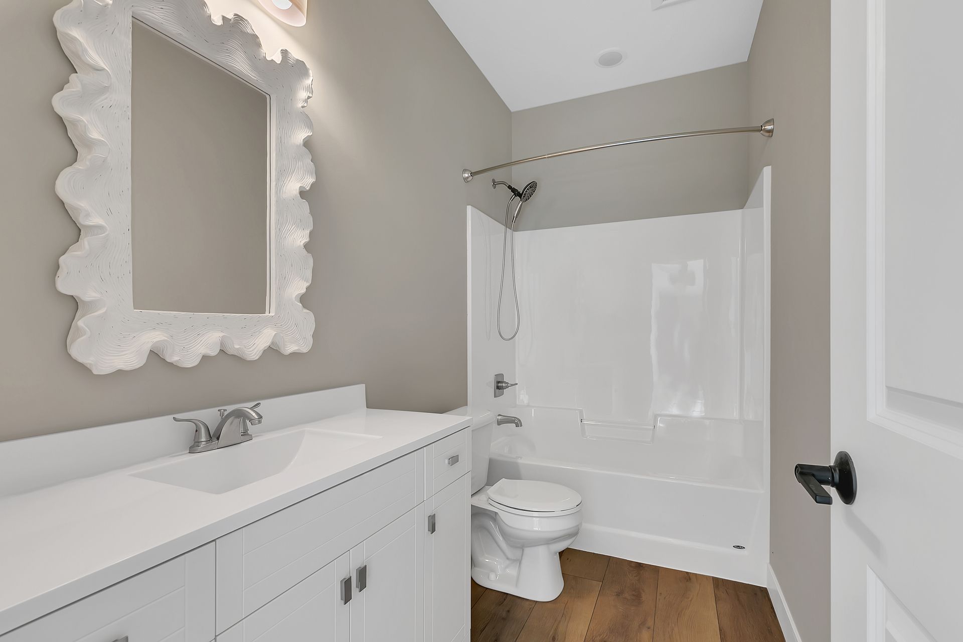 A bathroom with a toilet , sink , mirror and shower.