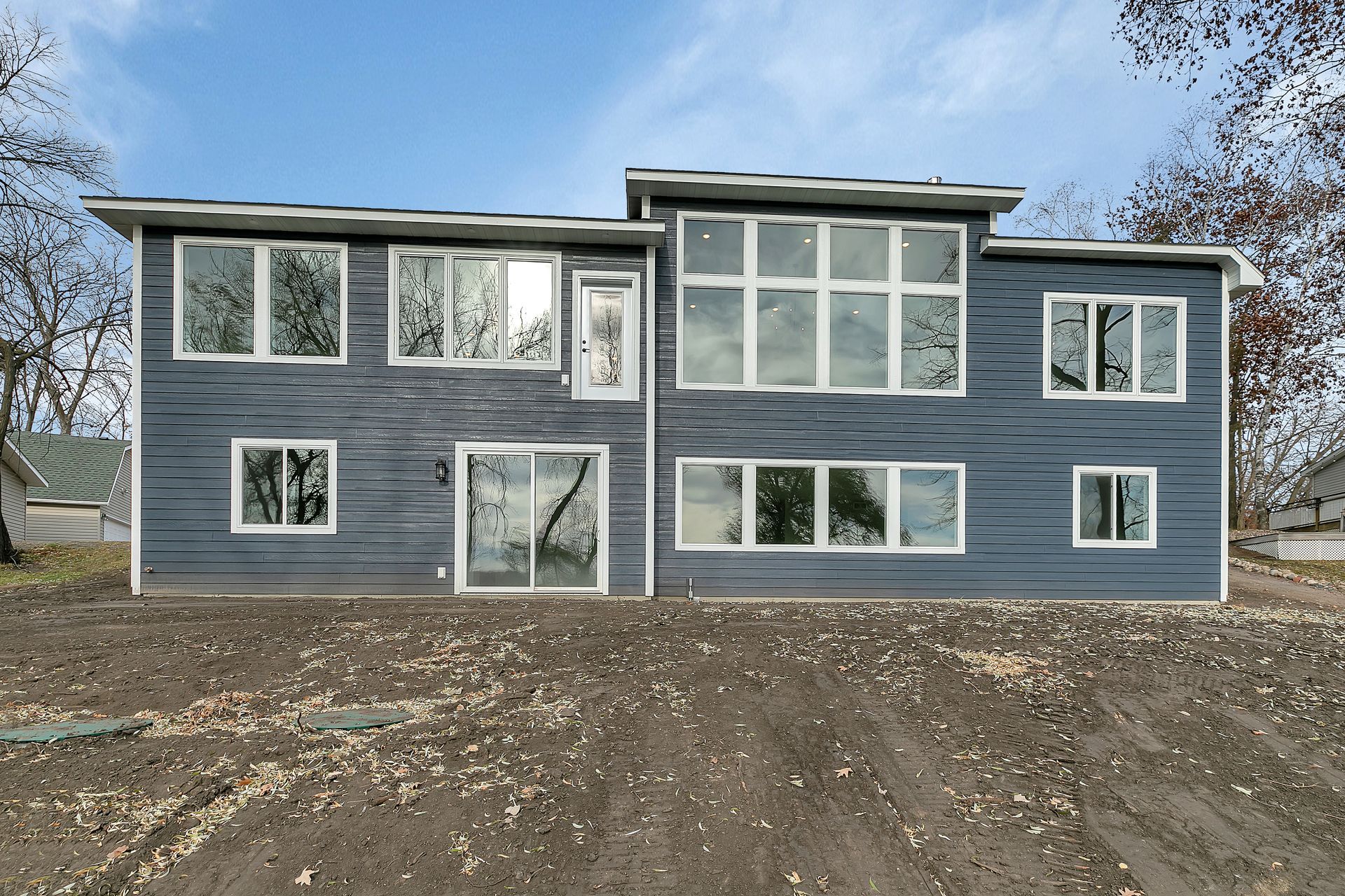 A large house with a lot of windows is sitting on top of a dirt hill