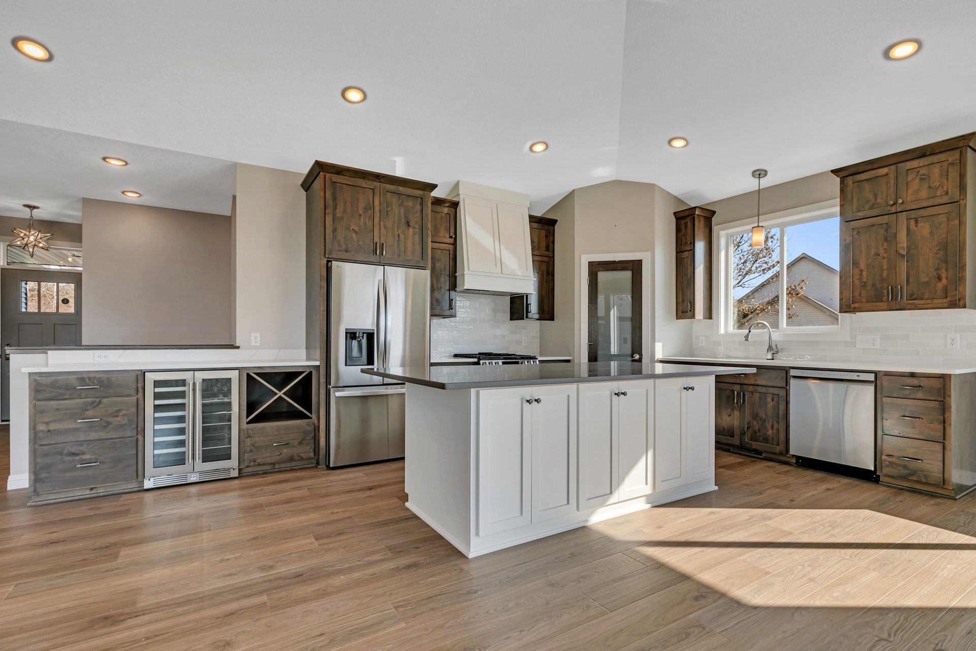 A kitchen with white cabinets and stainless steel appliances and a large island in the middle.