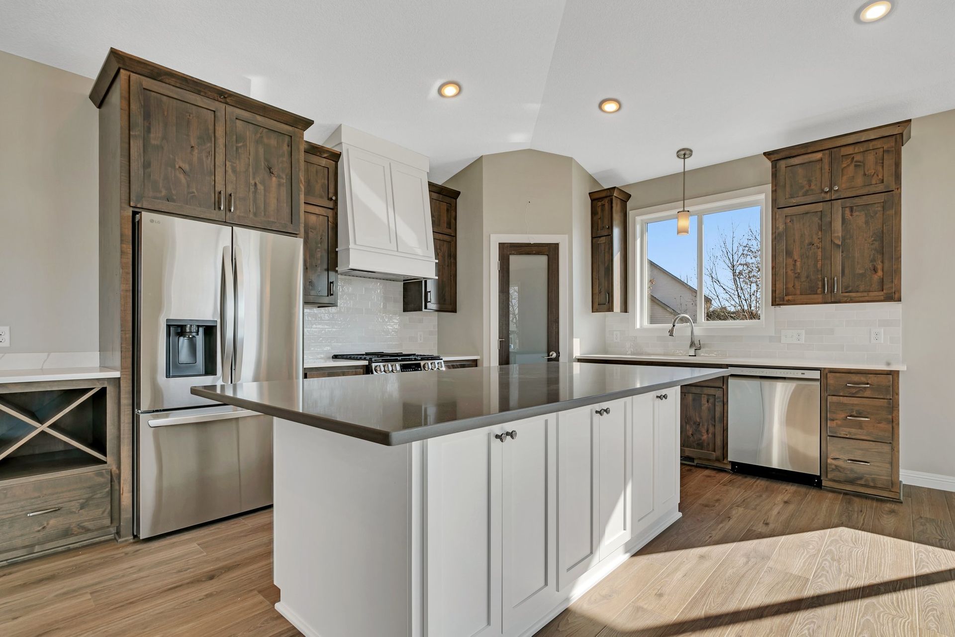 A kitchen with white cabinets , stainless steel appliances , and a large island.