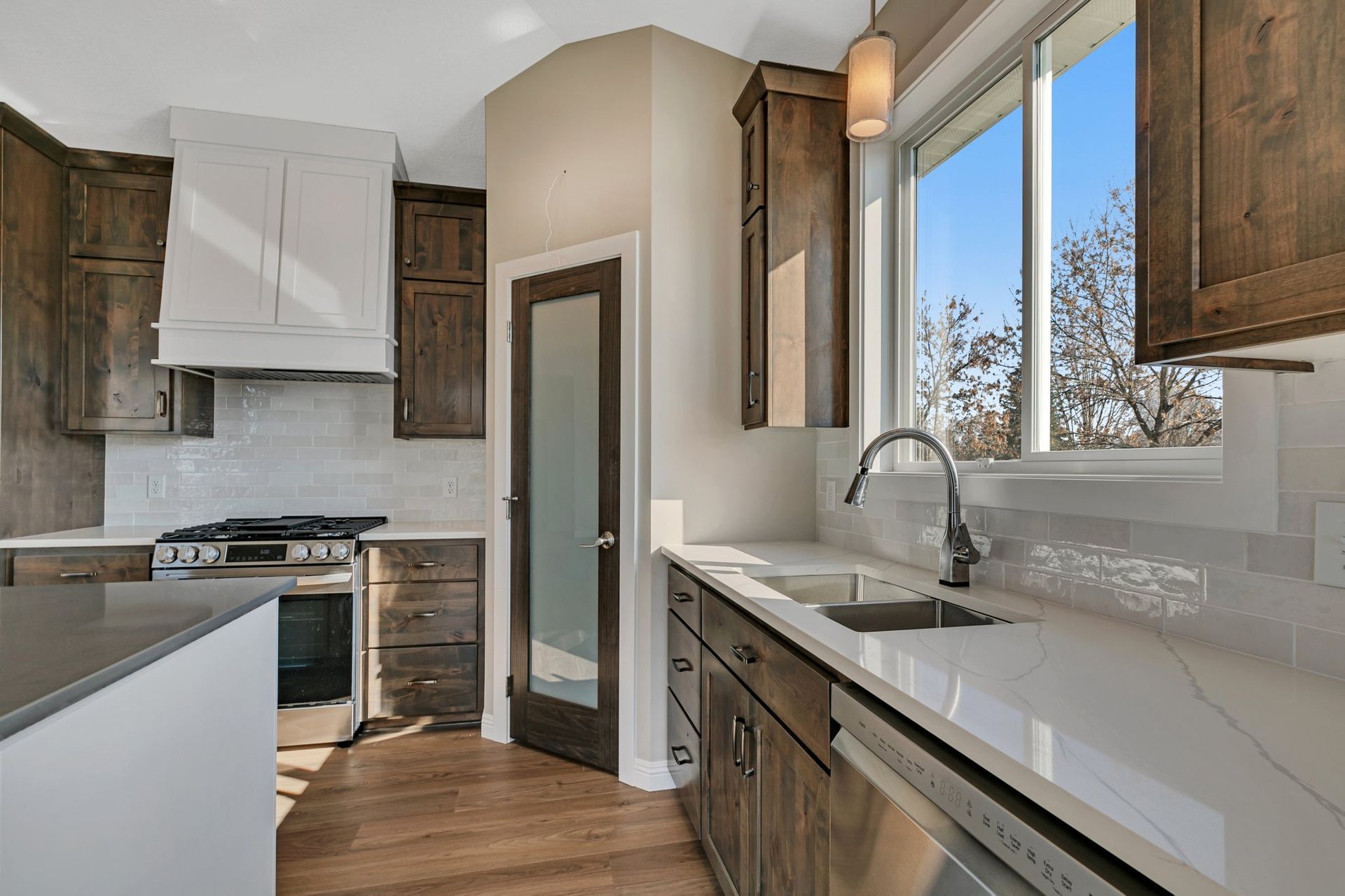 A kitchen with a sink , stove , dishwasher and window.
