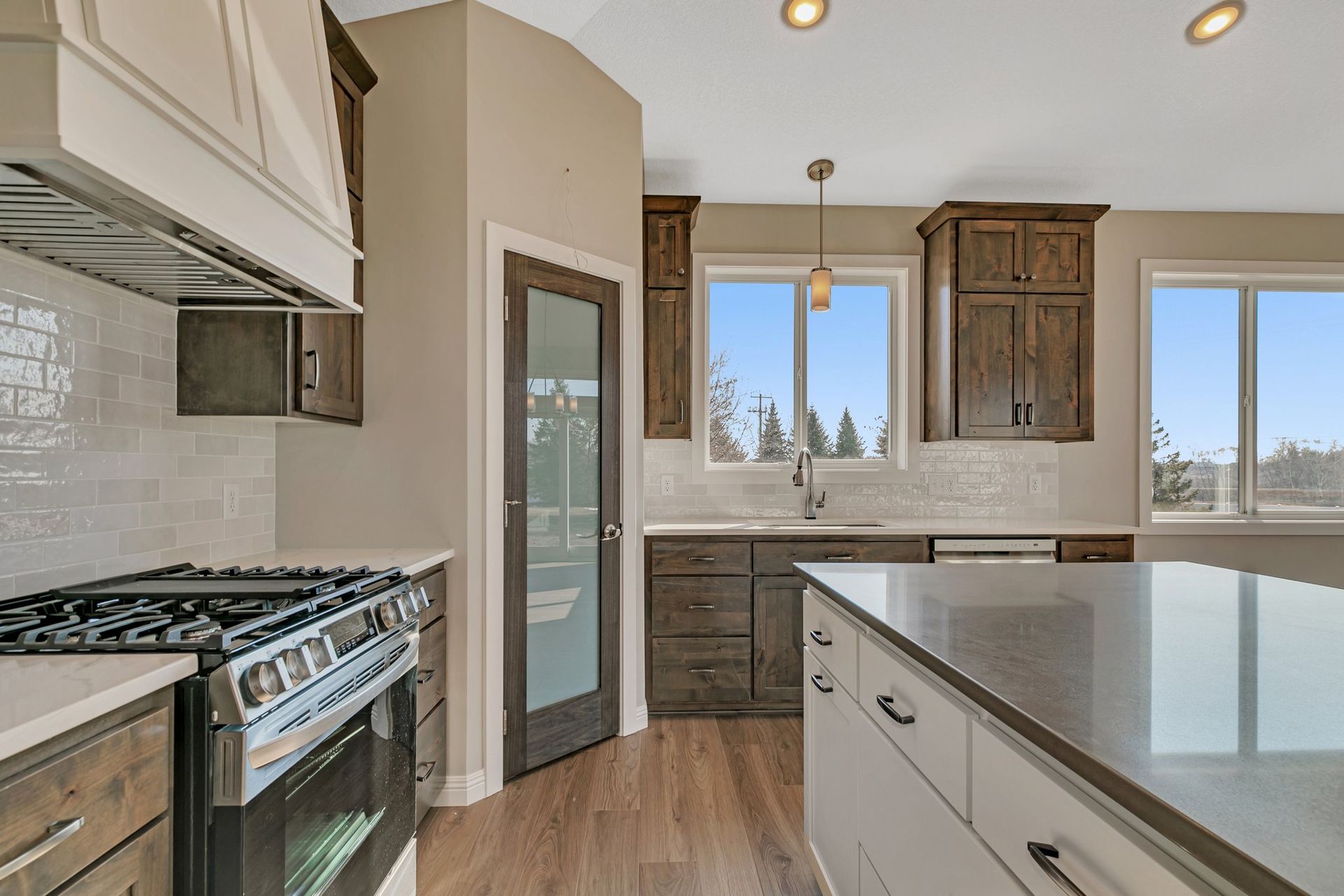 A kitchen with a stove , sink , cabinets and a large island.