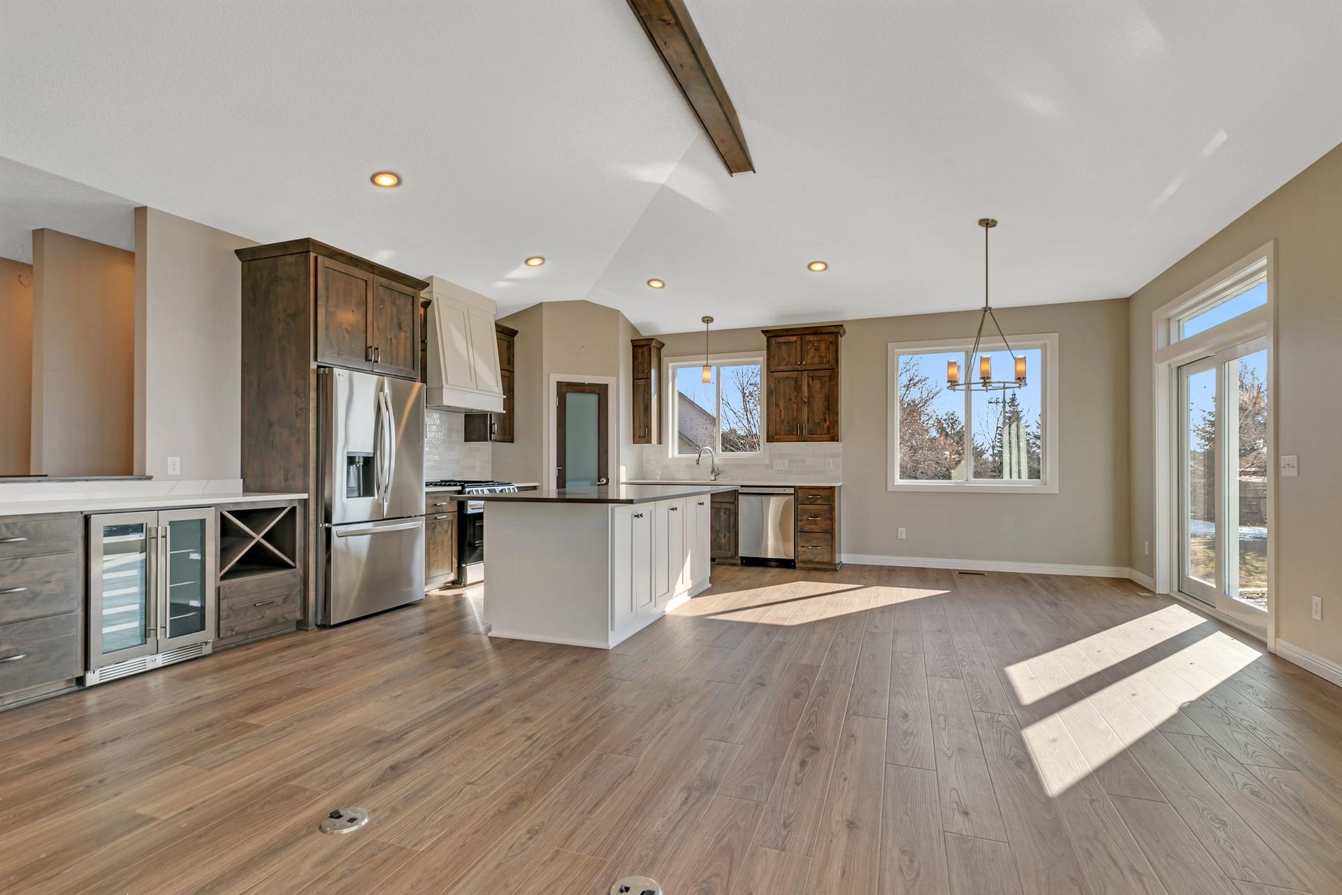 A kitchen and living room in a new home with hardwood floors and stainless steel appliances.