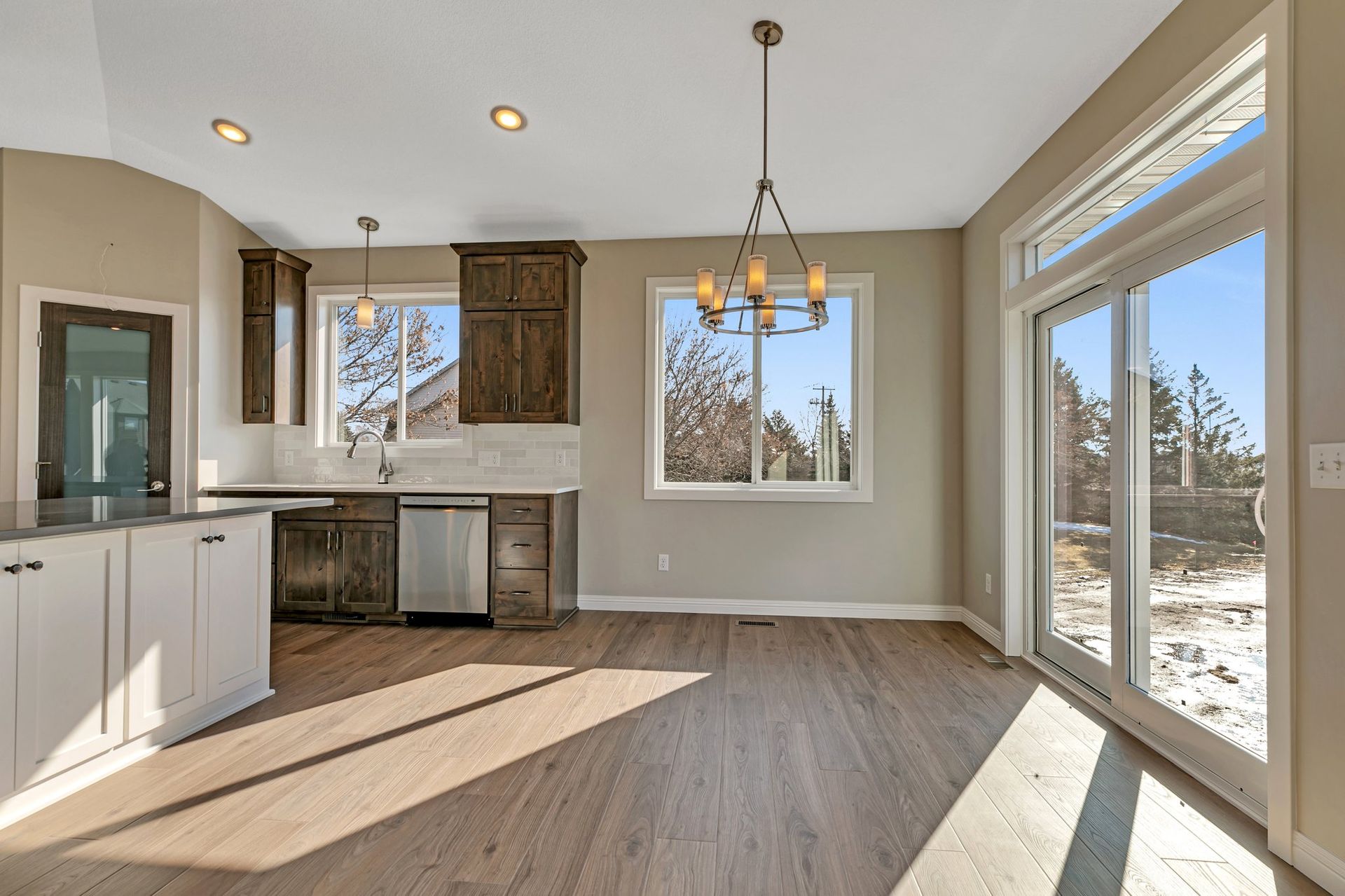 An empty kitchen with sliding glass doors and a chandelier hanging from the ceiling.