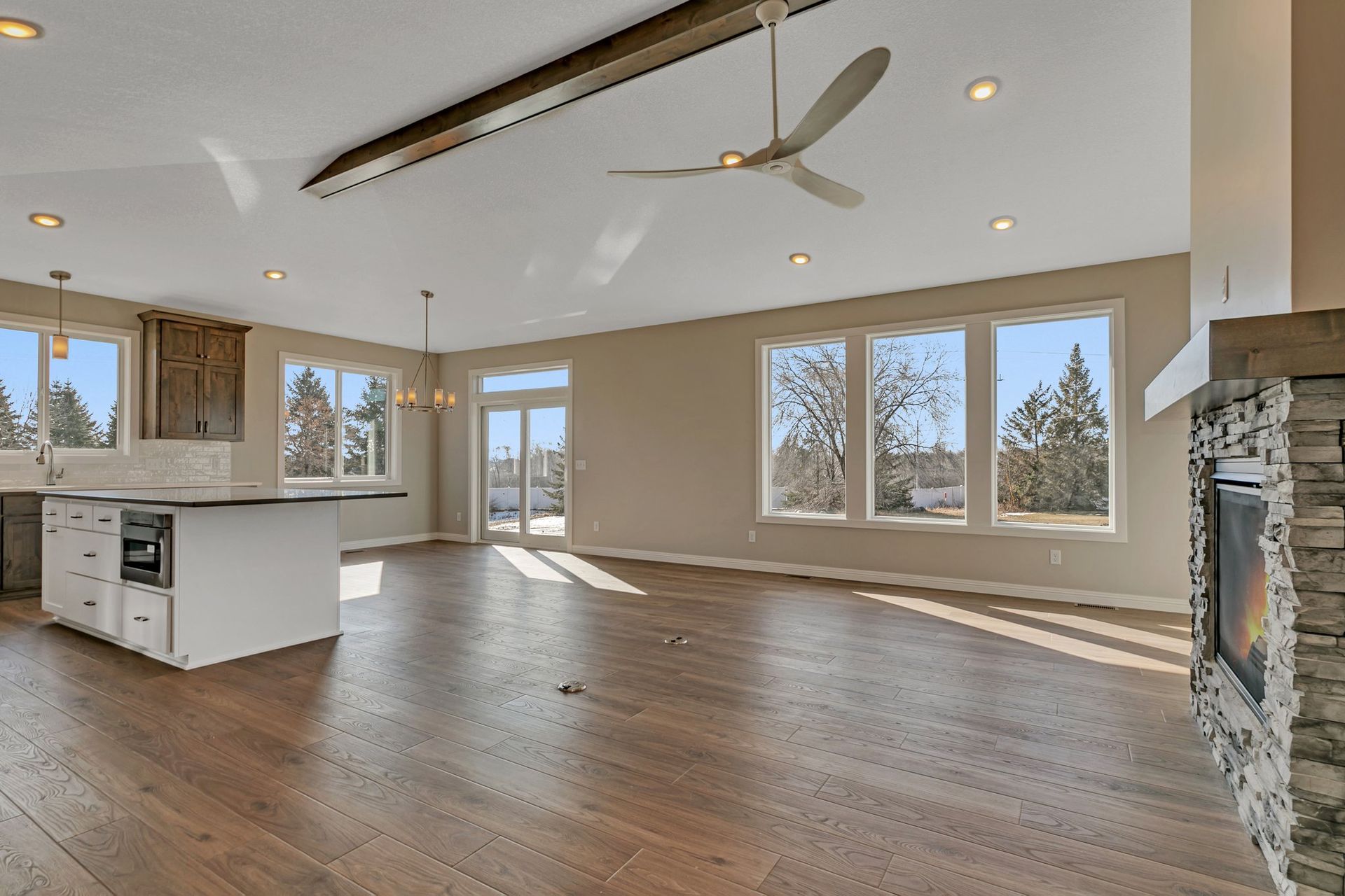 A large empty room with hardwood floors and a ceiling fan.