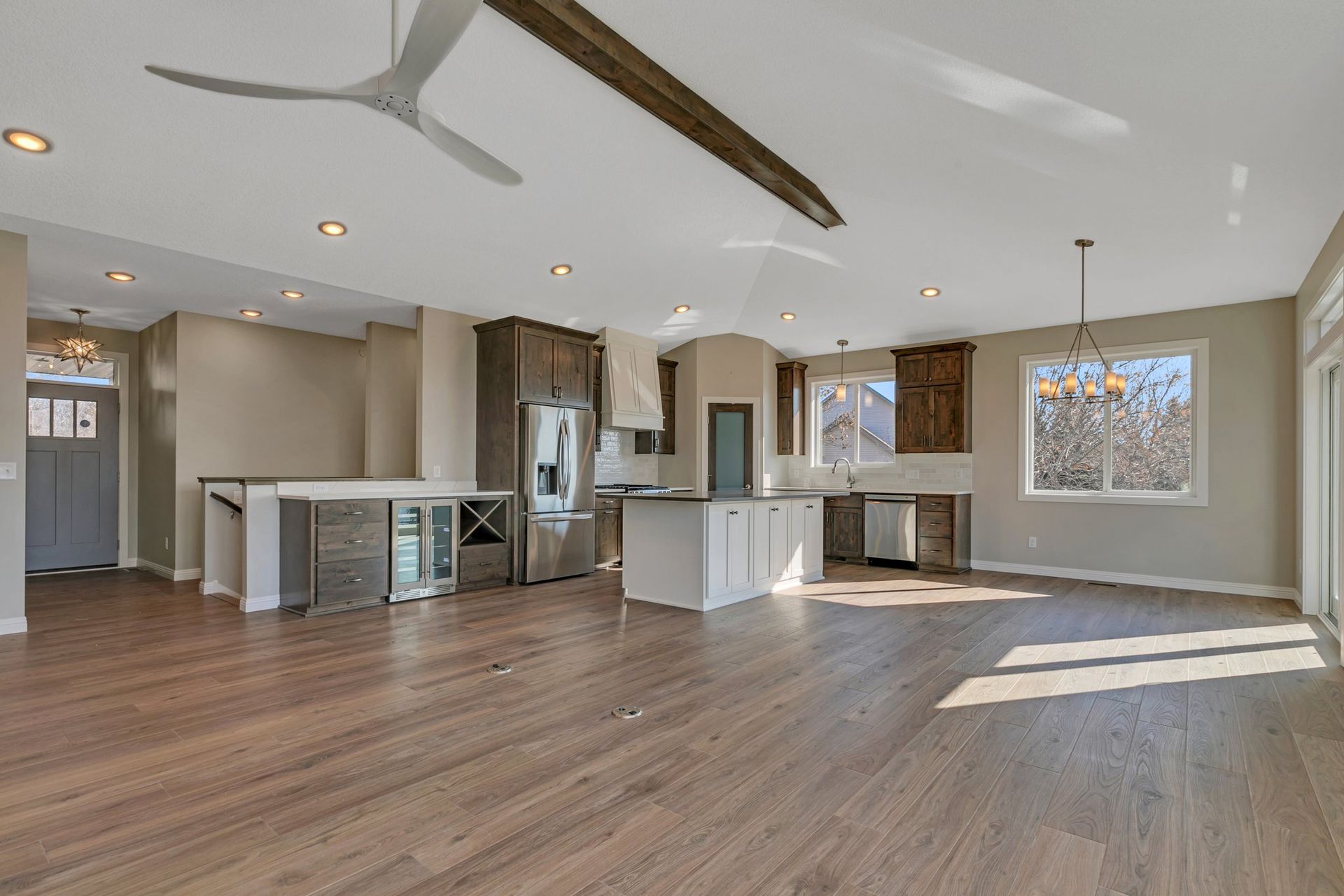 A large empty room with hardwood floors and a ceiling fan.