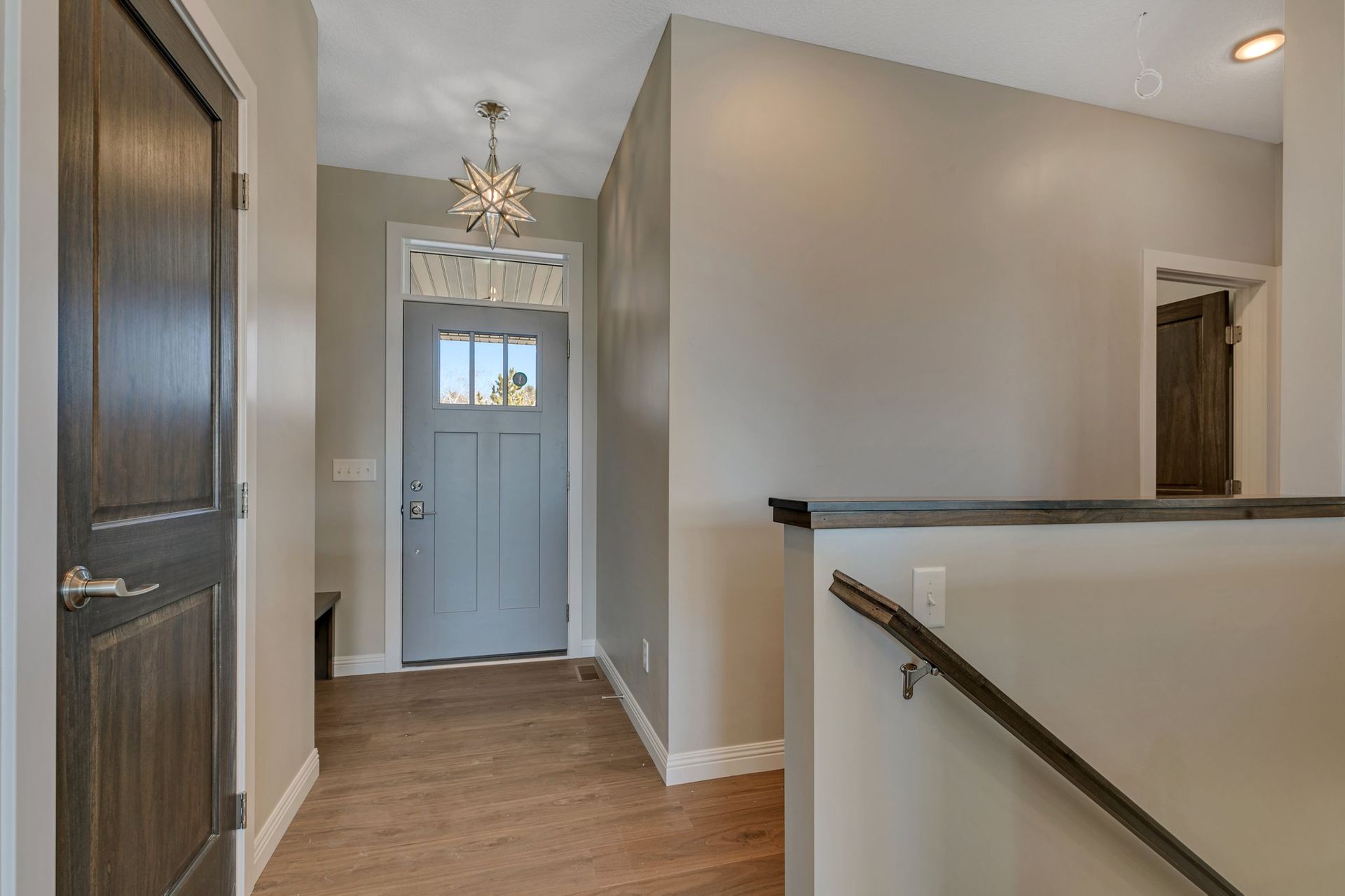 A hallway in a house with a blue door and stairs.