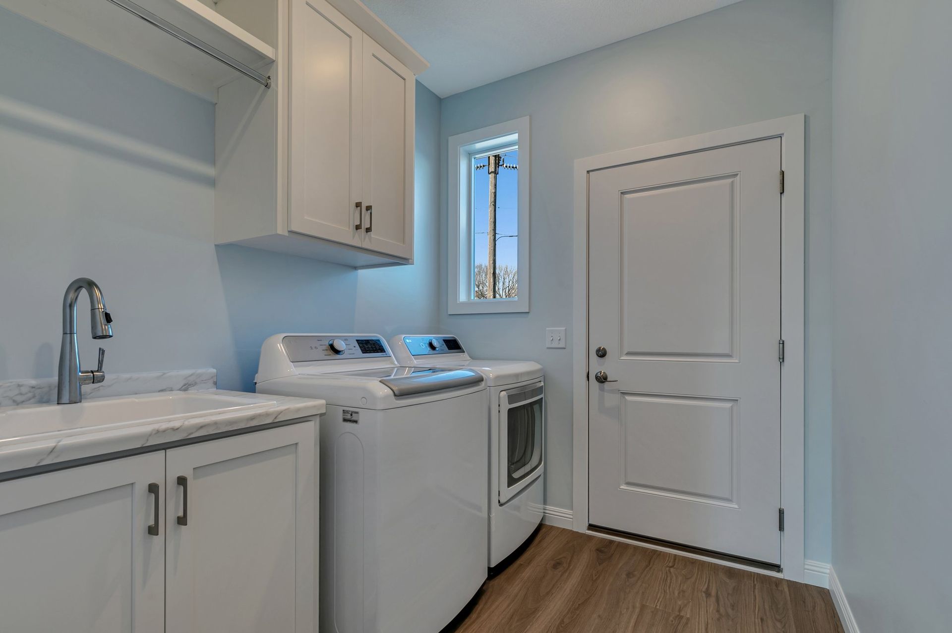 A laundry room with a washer and dryer , sink , and window.