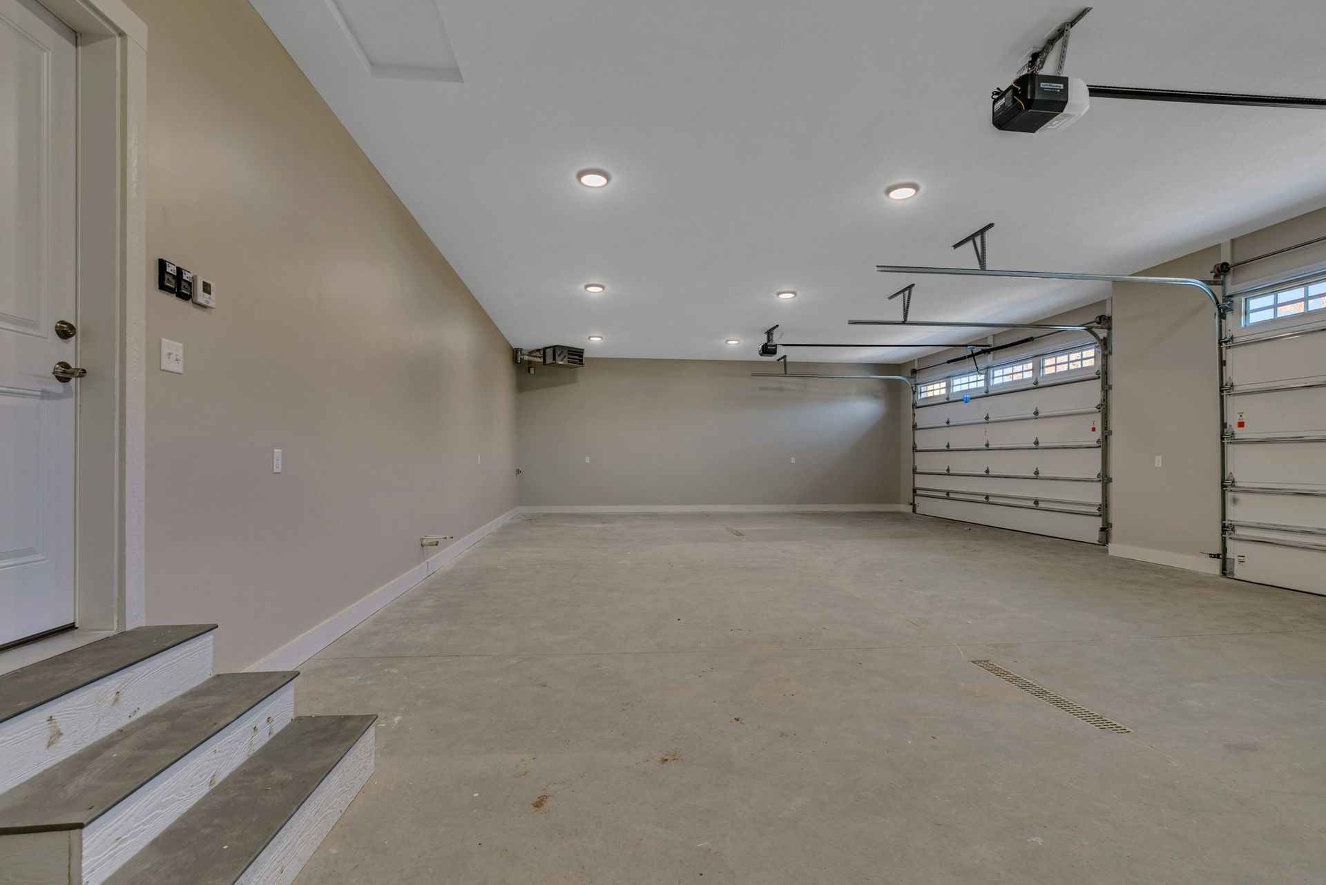 A large empty garage with stairs and a garage door open.