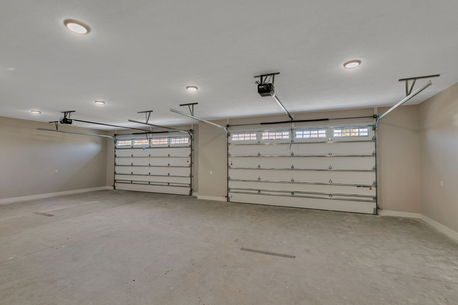 An empty garage with two garage doors and a ceiling fan.