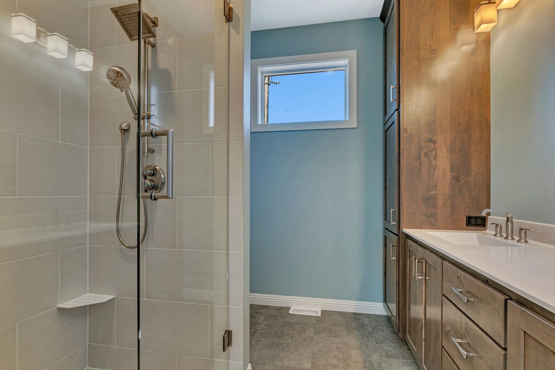 A bathroom with a walk in shower and a sink.