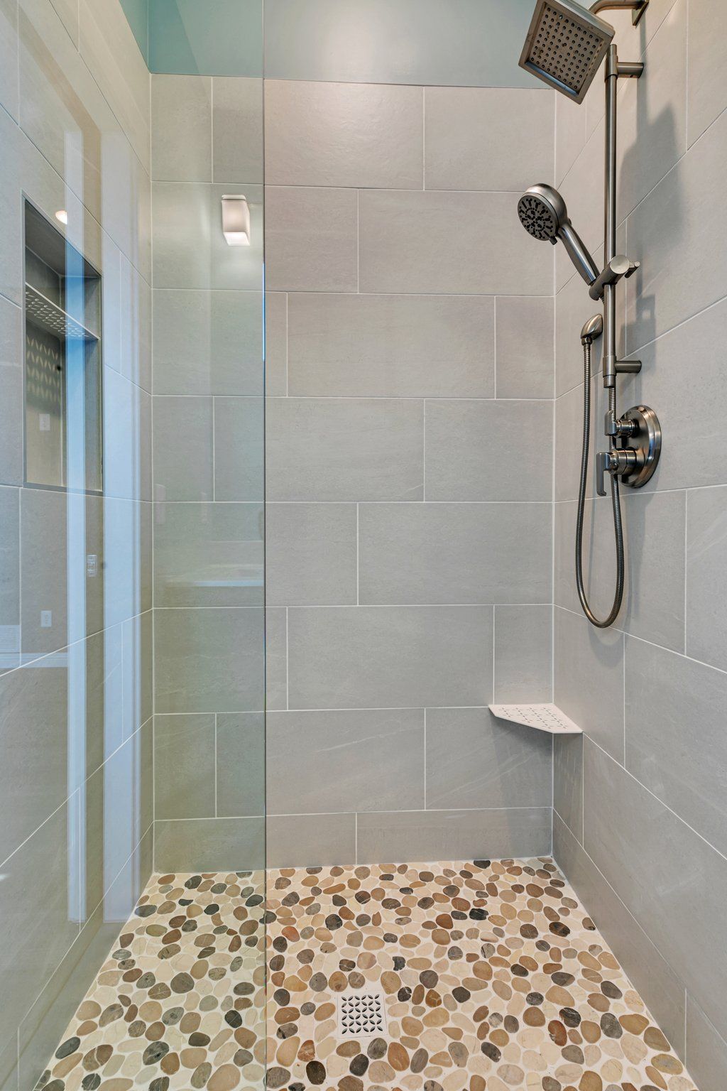 A walk in shower with a tiled floor and a shower head.