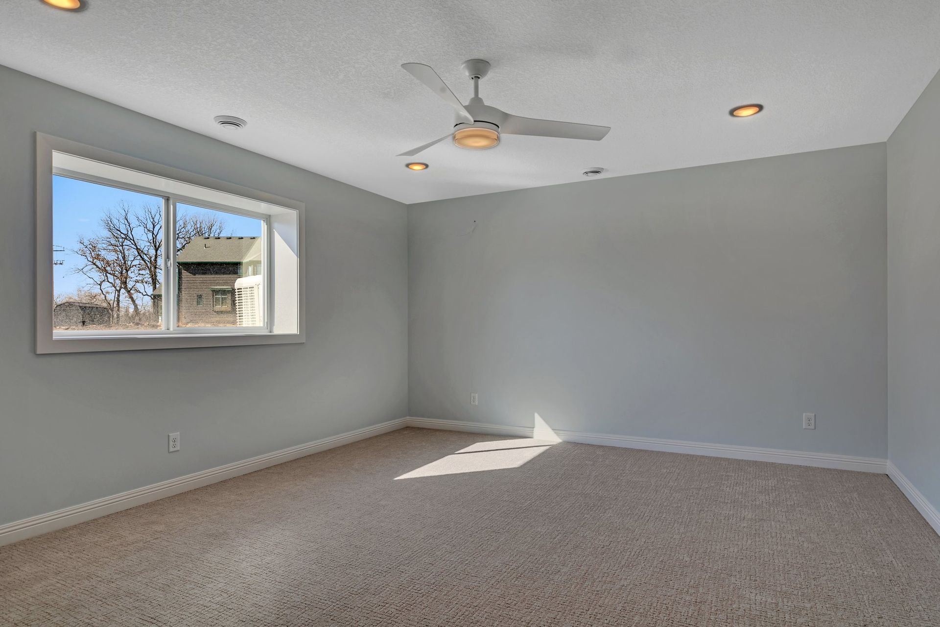 An empty room with a ceiling fan and a window.
