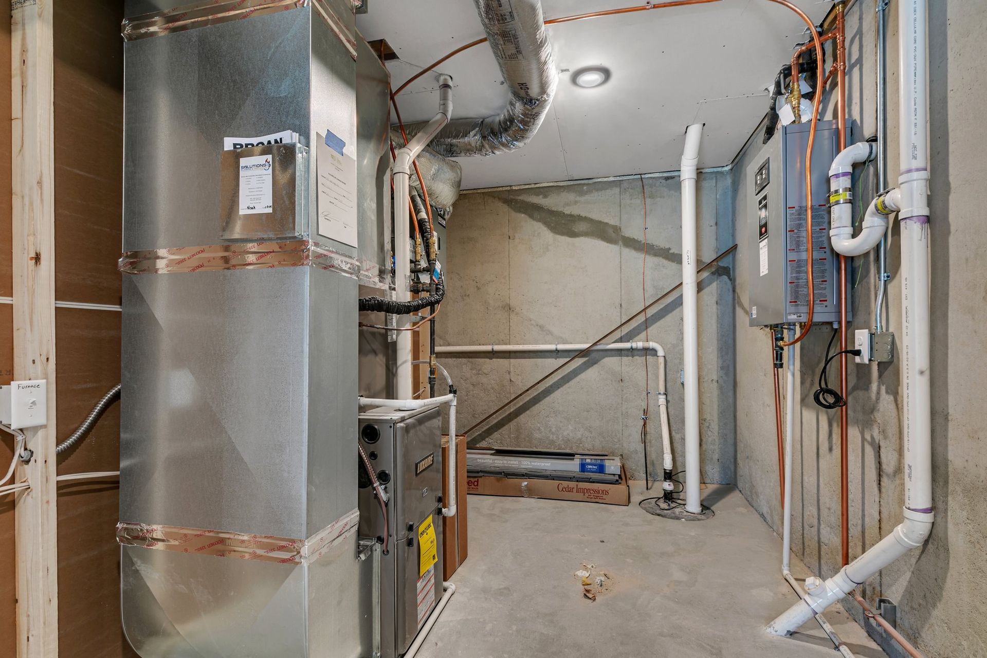 A basement with a furnace and pipes in it.