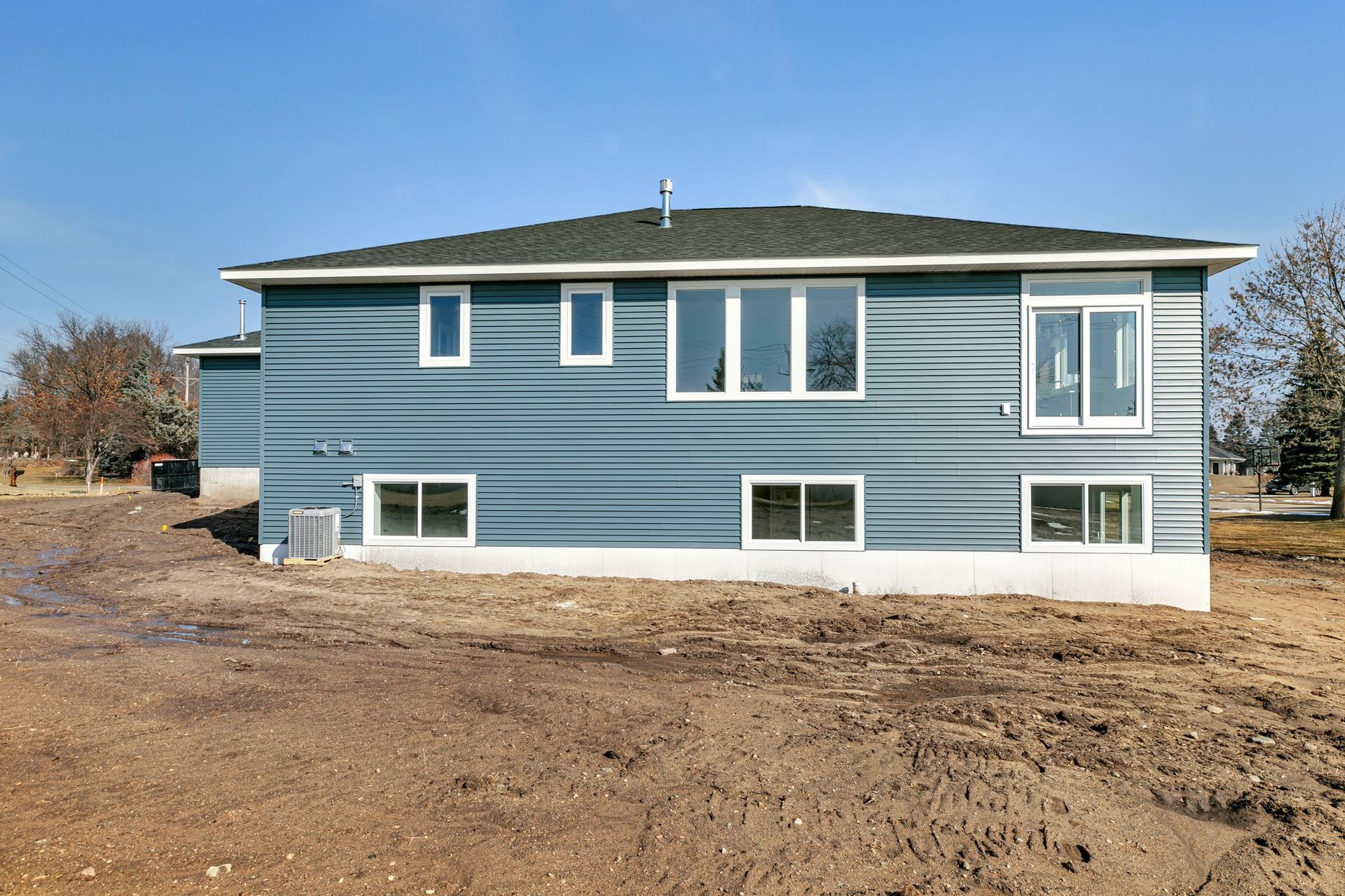 A blue house is sitting in the middle of a dirt field.