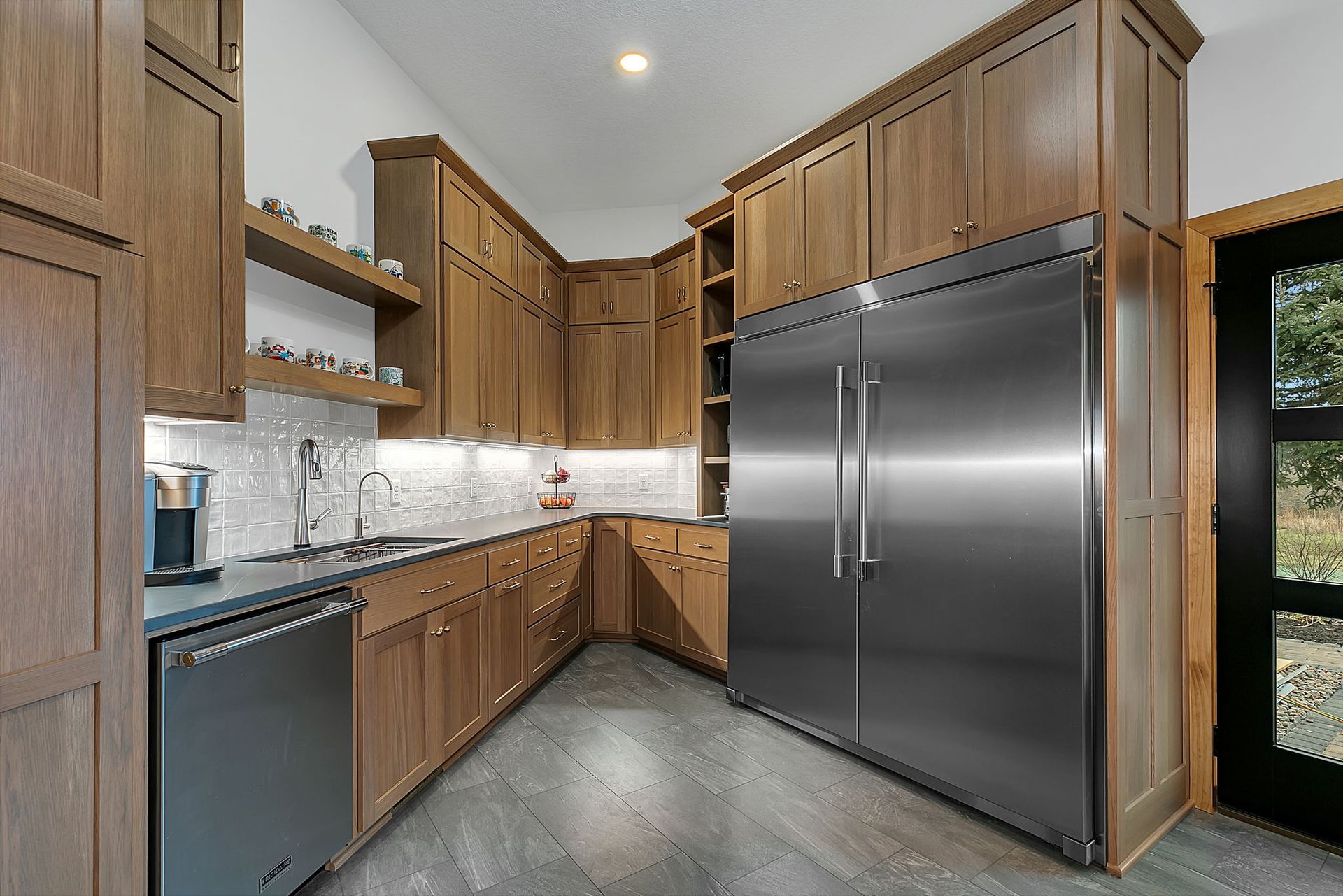 Kitchen with wood cabinets, stainless steel appliances, and gray flooring.