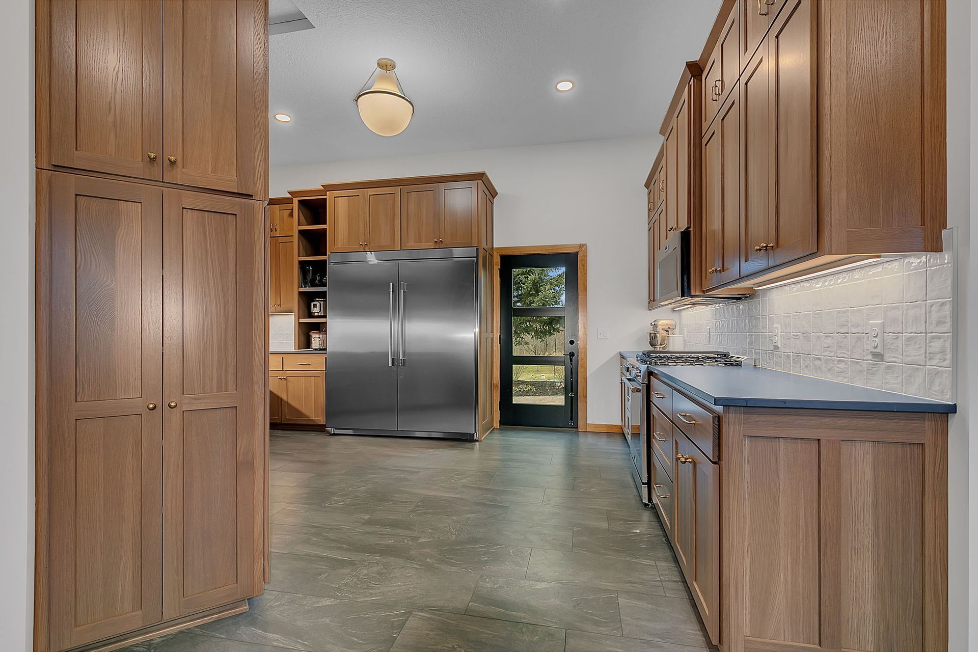 Kitchen with wood cabinets, stainless steel fridge, and dark gray floor.