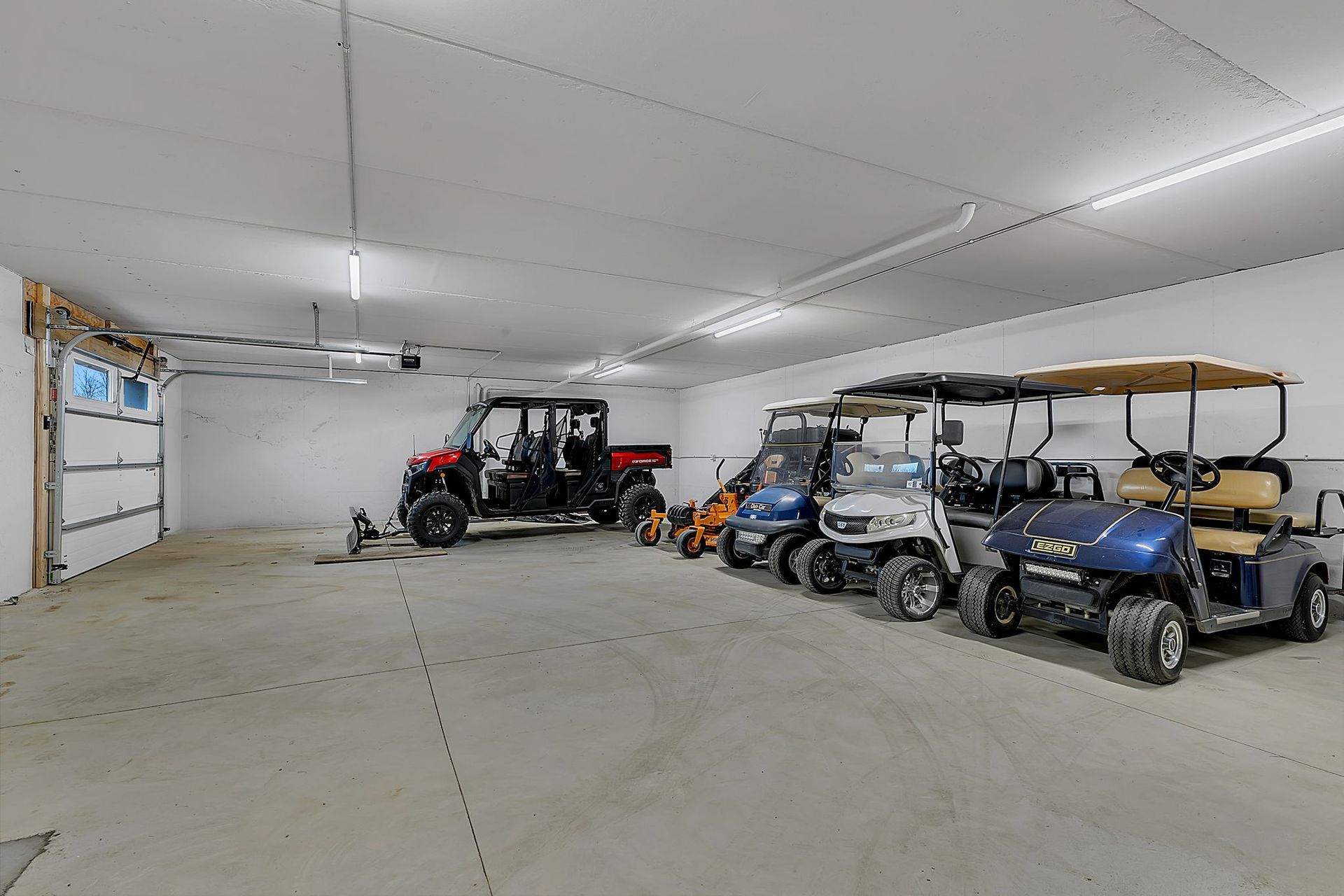 Garage with multiple golf carts and a side-by-side vehicle.