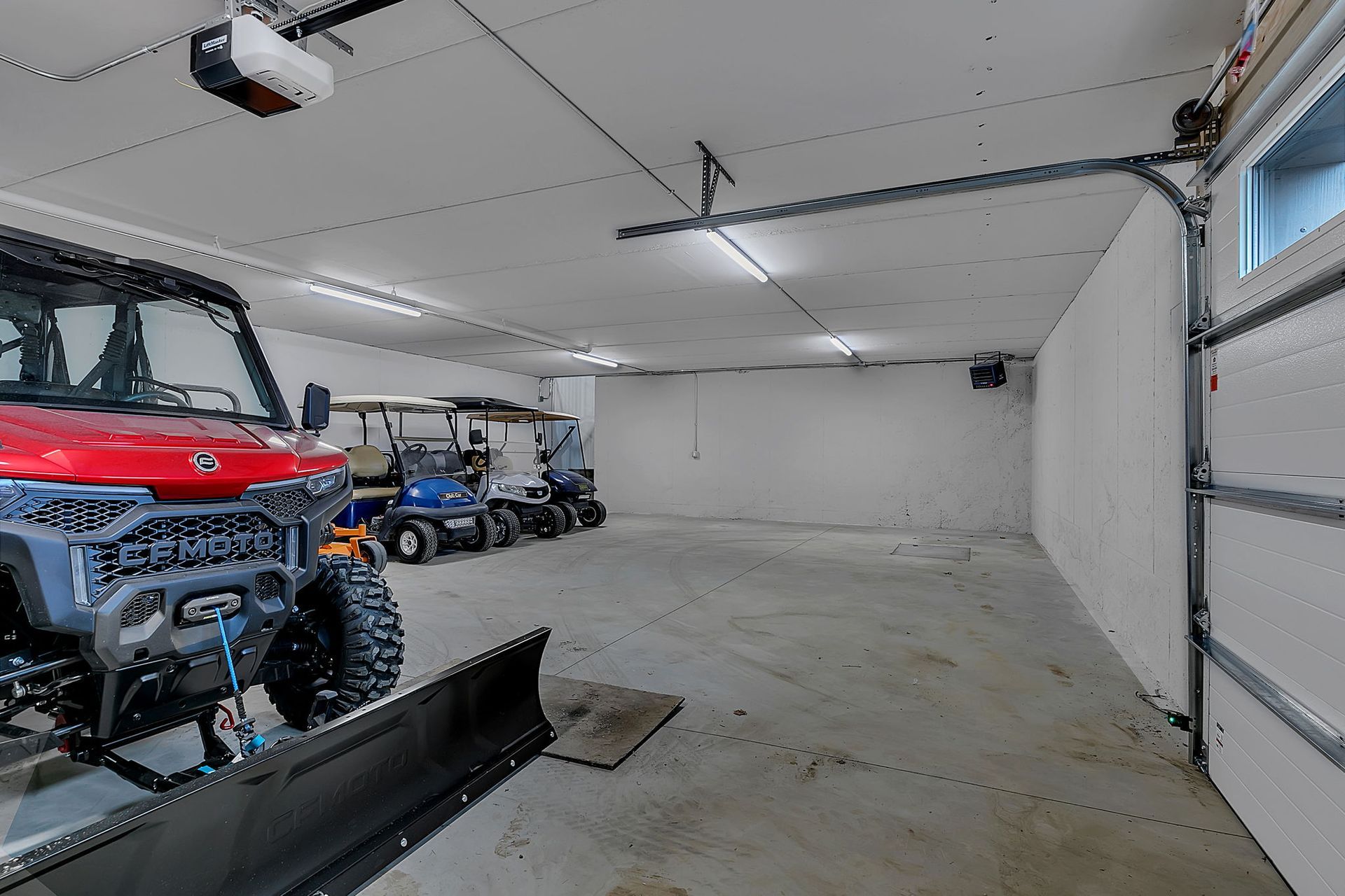 Garage with utility vehicle, golf carts, and snowplow.