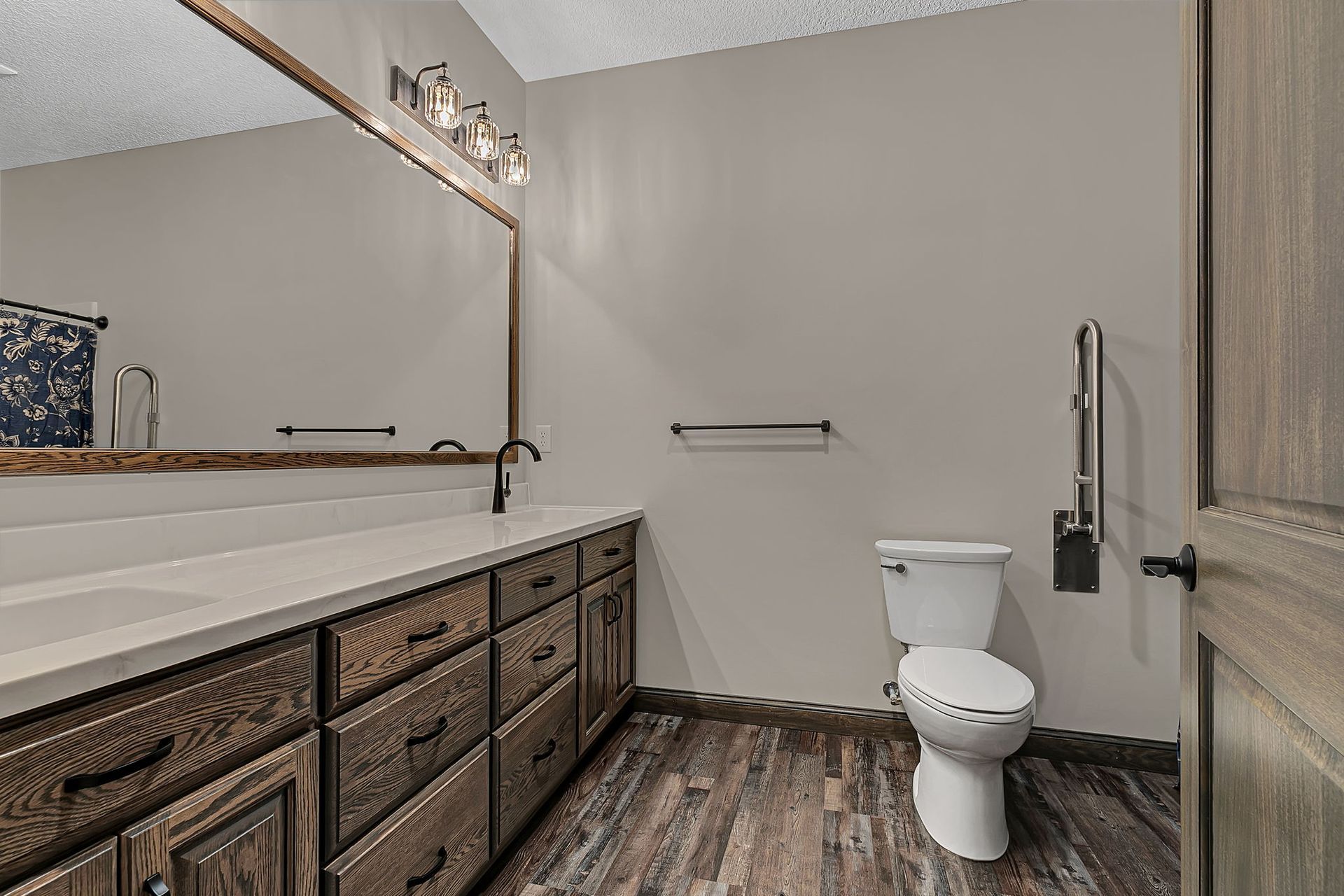 Bathroom with wooden vanity, toilet, and accessibility grab bar.
