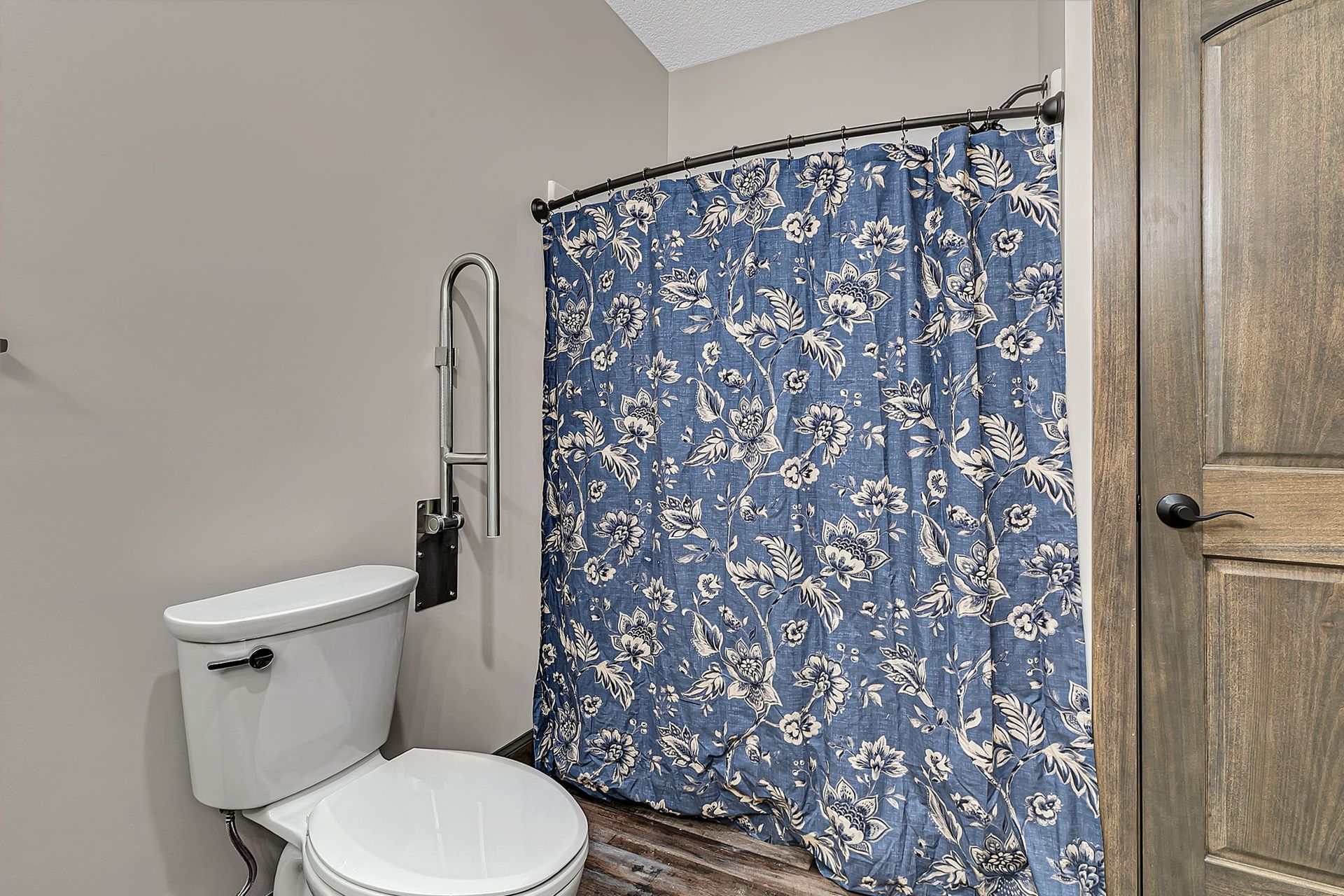 Bathroom with a toilet, shower curtain, and a brown wooden door.