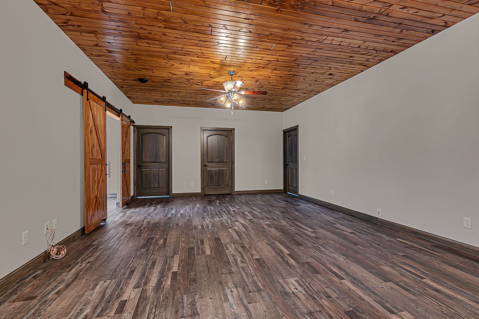 Spacious room with wood floors, brown doors, and a decorative ceiling.