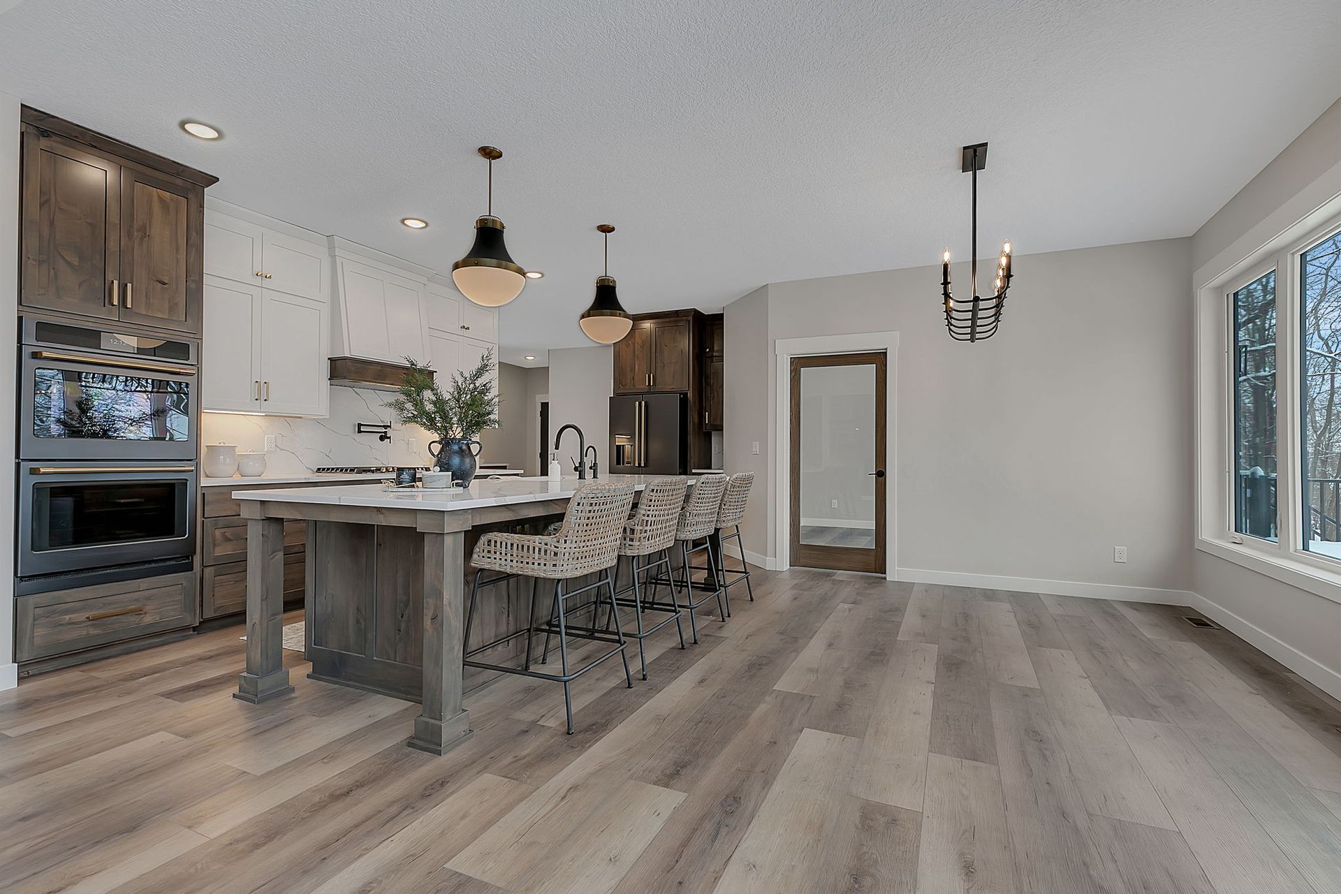 Kitchen with wood cabinetry, island with bar stools, and large windows.