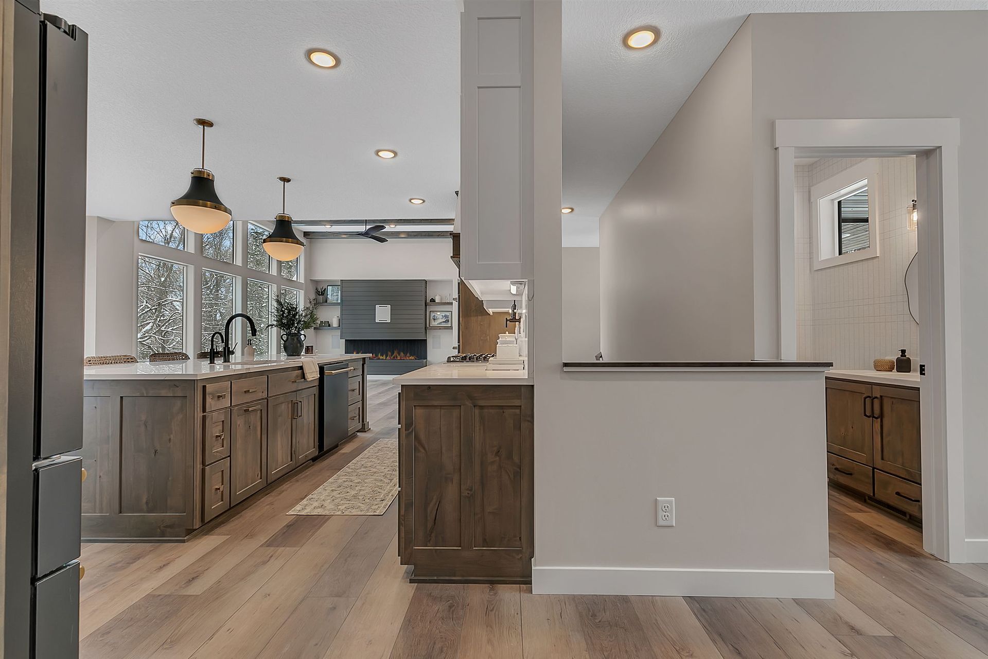 Kitchen interior with wooden cabinets, light gray walls, pendant lights, and hardwood floors.