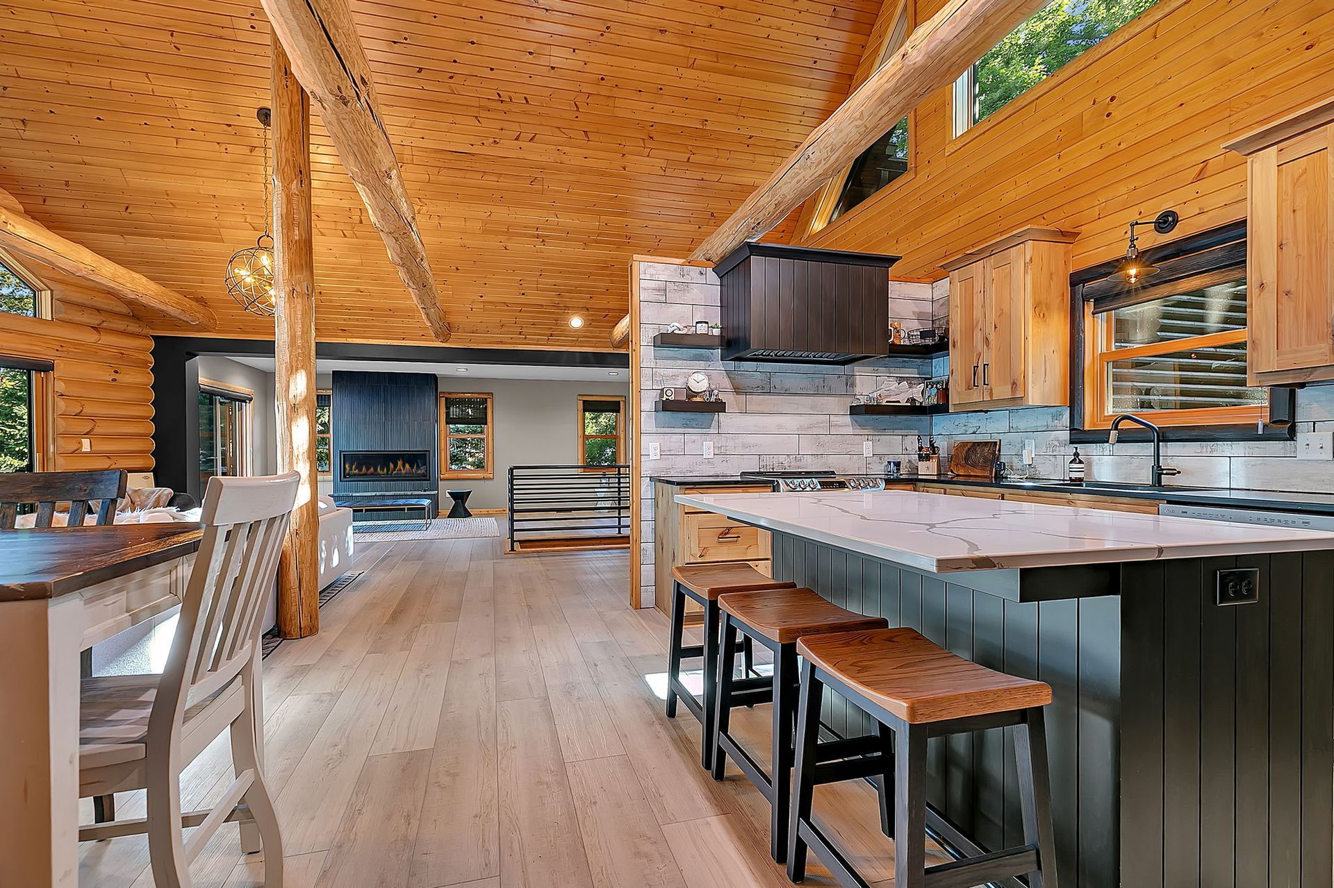 Modern rustic kitchen with wood ceilings, island seating, and open shelving