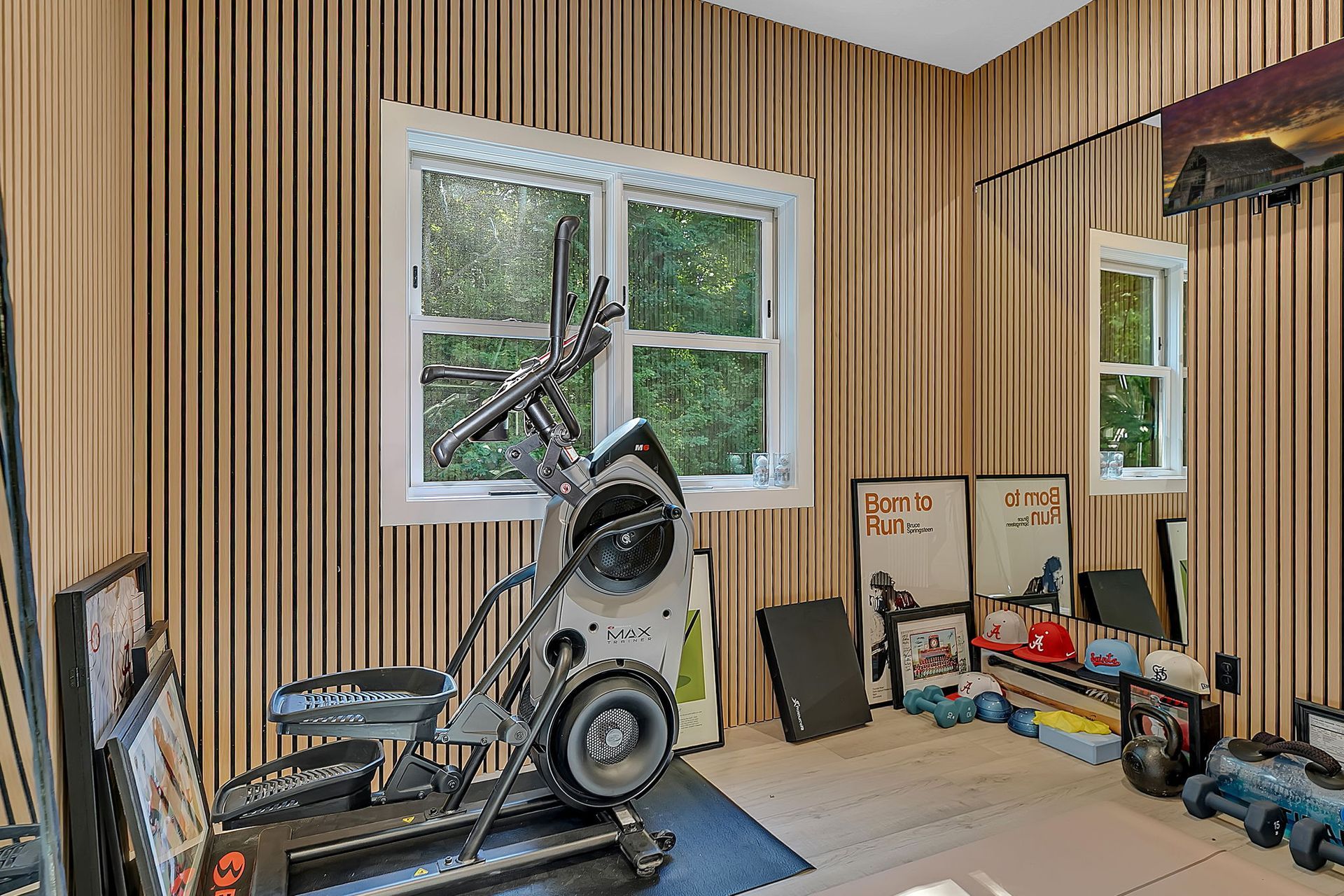 Workout room with an exercise bike, treadmill, and equipment against striped walls by a window.
