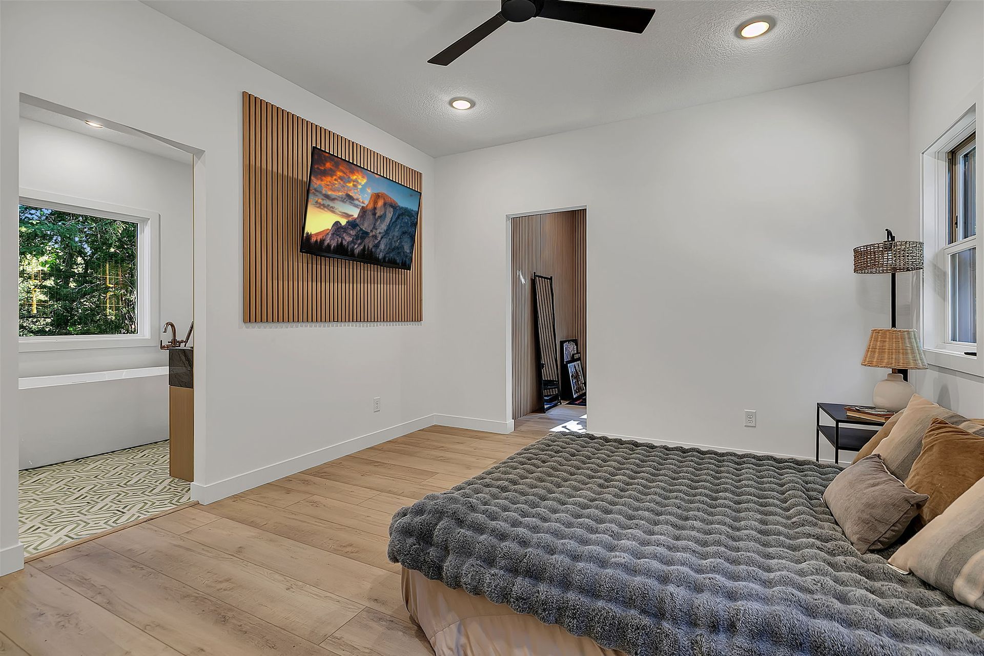 Modern bedroom with bed, wall art, mirrored closet, and windows letting in natural light