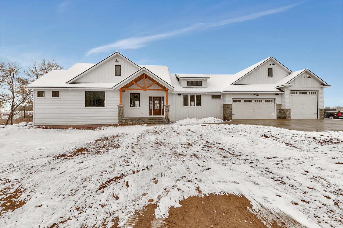 A large white house is sitting on top of a snow covered field.