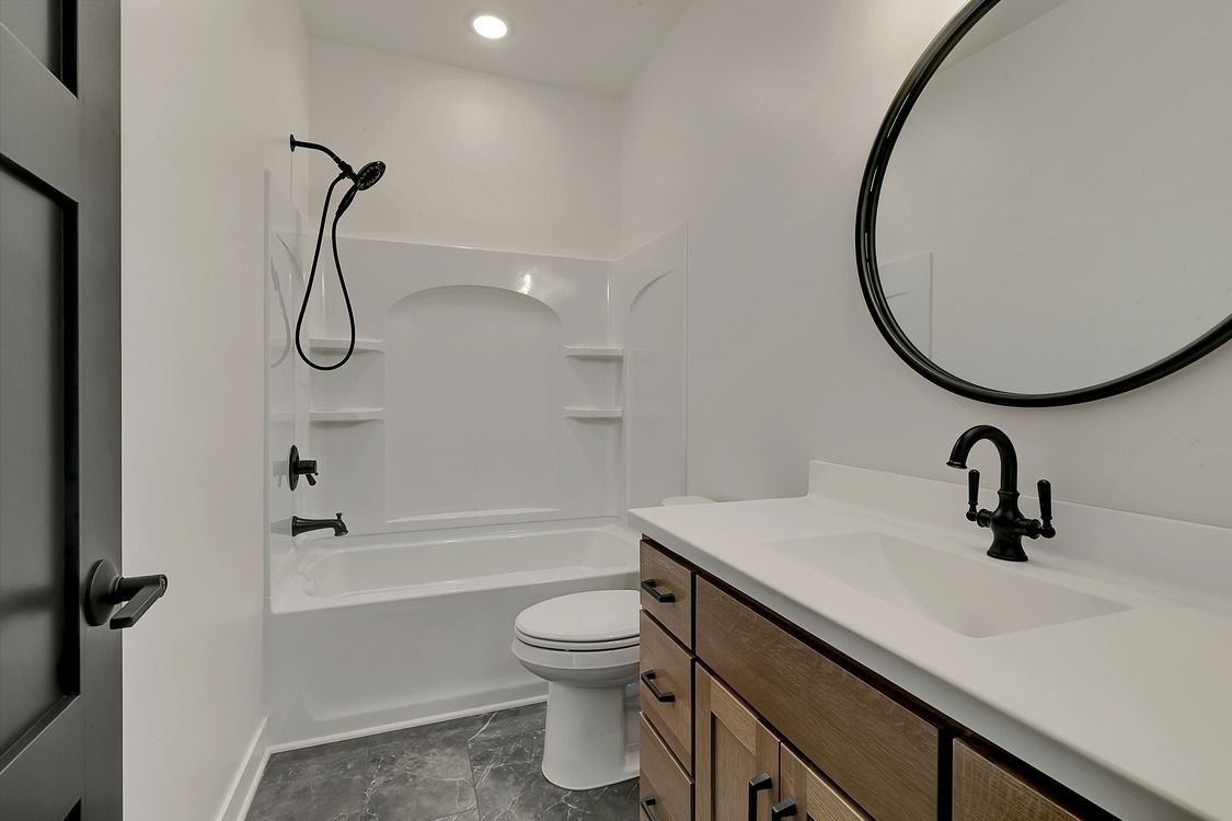 A bathroom with a toilet , sink , shower and mirror.