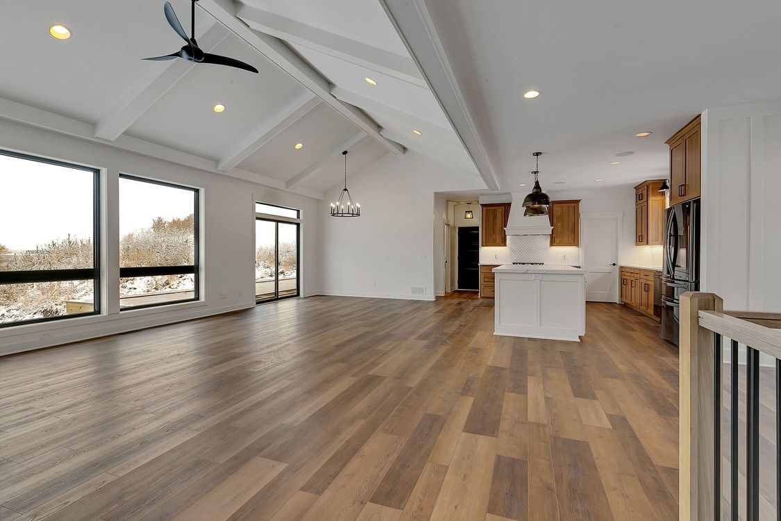 A large empty room with hardwood floors and a ceiling fan.