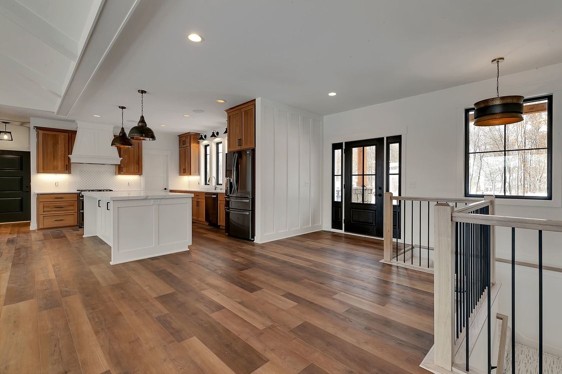 A kitchen with hardwood floors and white cabinets in a house.