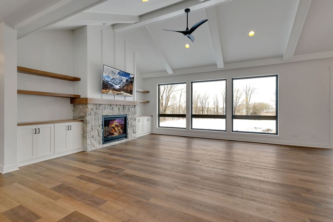 An empty living room with hardwood floors , a fireplace , and a ceiling fan.