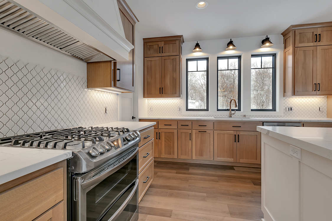 A kitchen with wooden cabinets , stainless steel appliances , a stove and a sink.