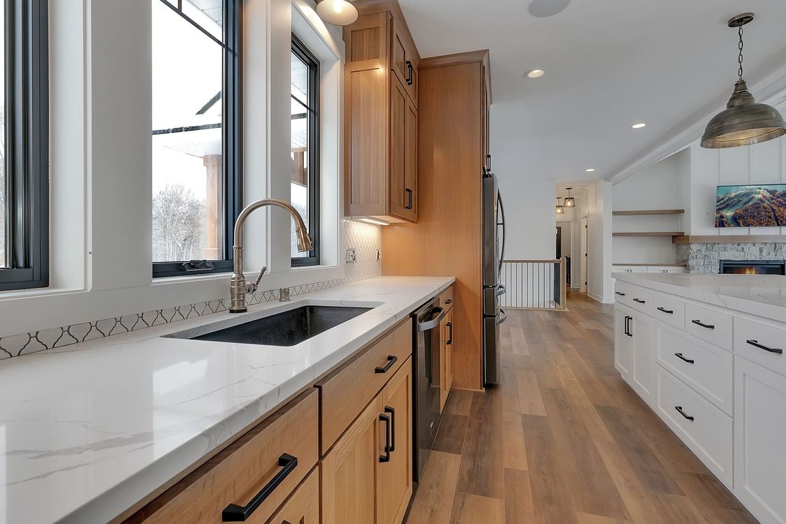 A kitchen with wooden cabinets , white counter tops , and a sink.