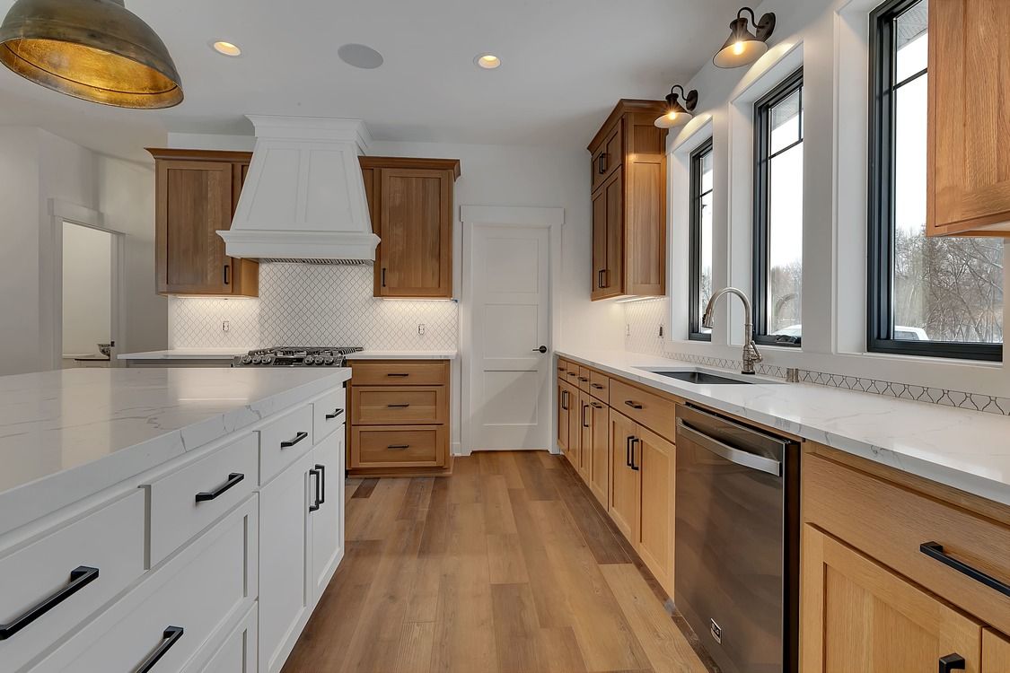 A kitchen with wooden cabinets , white counter tops , and stainless steel appliances.
