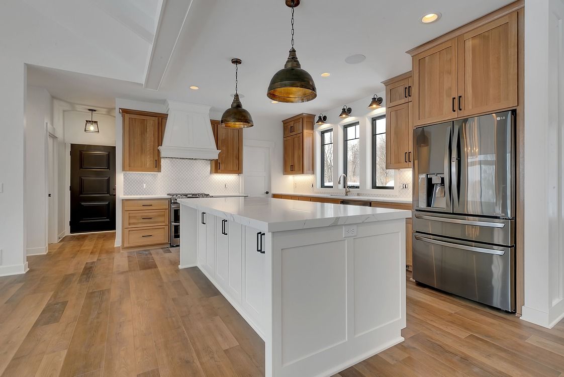 A kitchen with a large island , stainless steel appliances , wooden cabinets and hardwood floors.