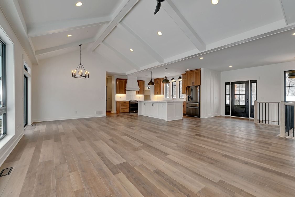 A large empty room with hardwood floors and a vaulted ceiling.
