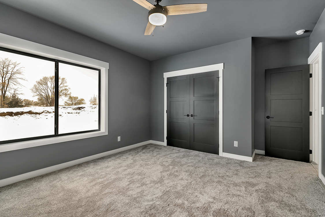 An empty bedroom with a ceiling fan and two windows.