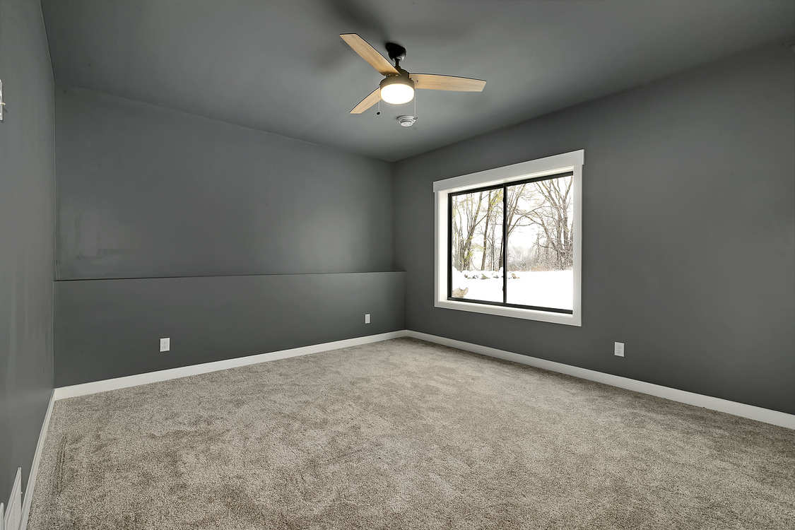 An empty bedroom with a ceiling fan and a window.