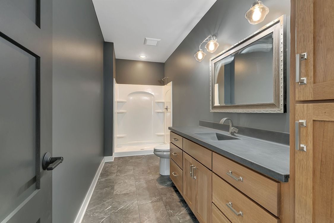 A bathroom with a sink , mirror and shower.