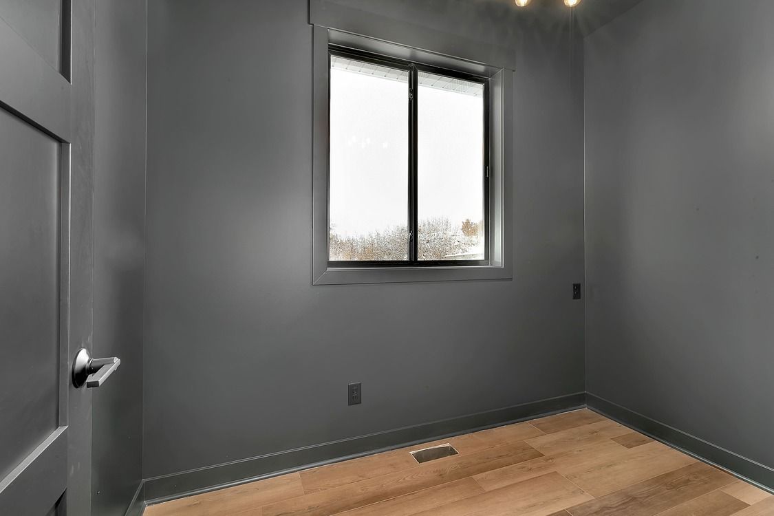 An empty room with gray walls and a window.