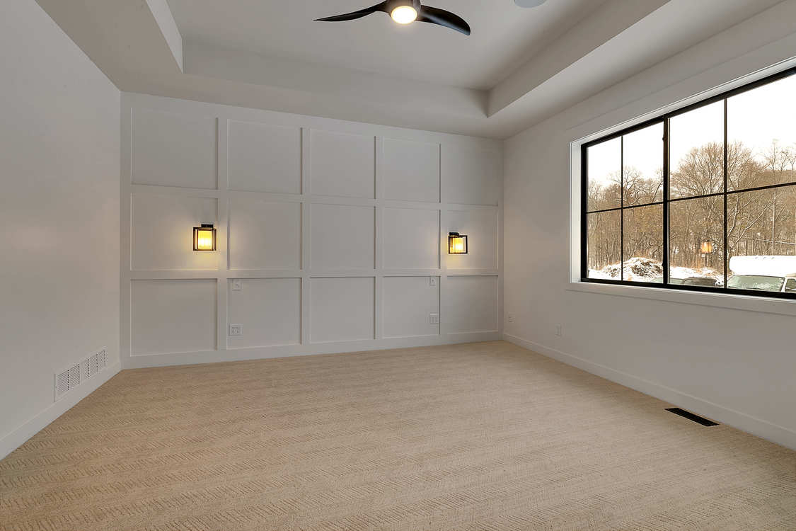 An empty bedroom with a ceiling fan and a large window.
