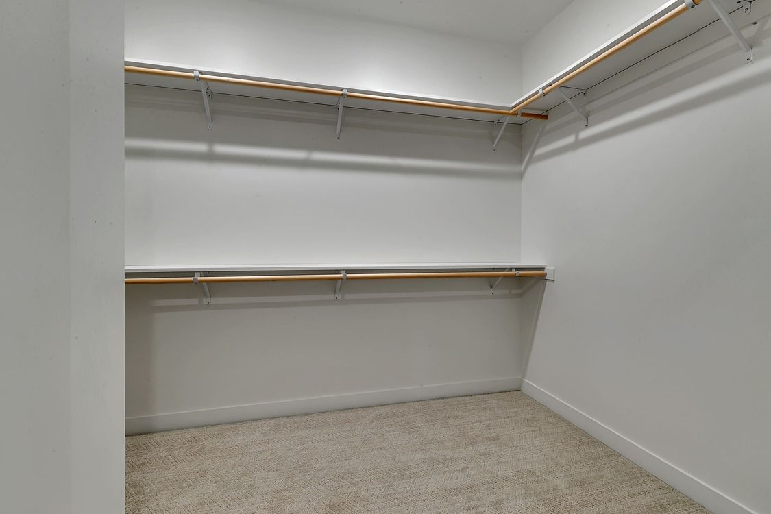A walk in closet with a carpeted floor and wooden shelves.